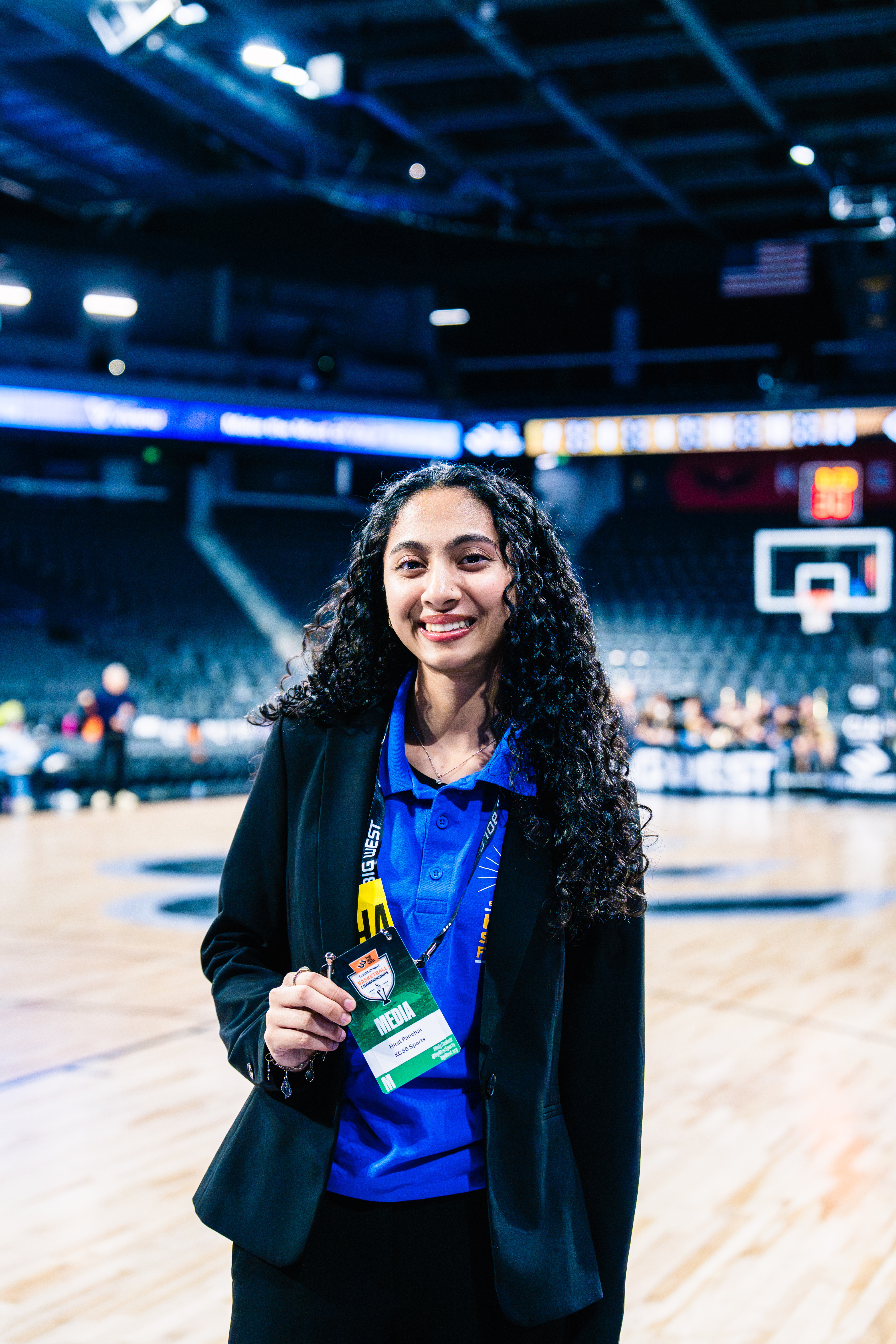 Girl standing in basketball stadium holding her media pass.