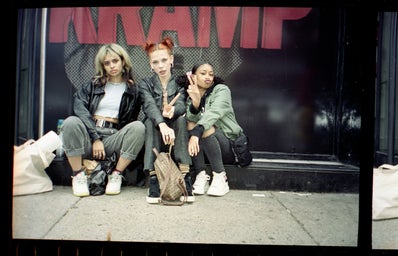 three girls sitting on the street and posing for a picture