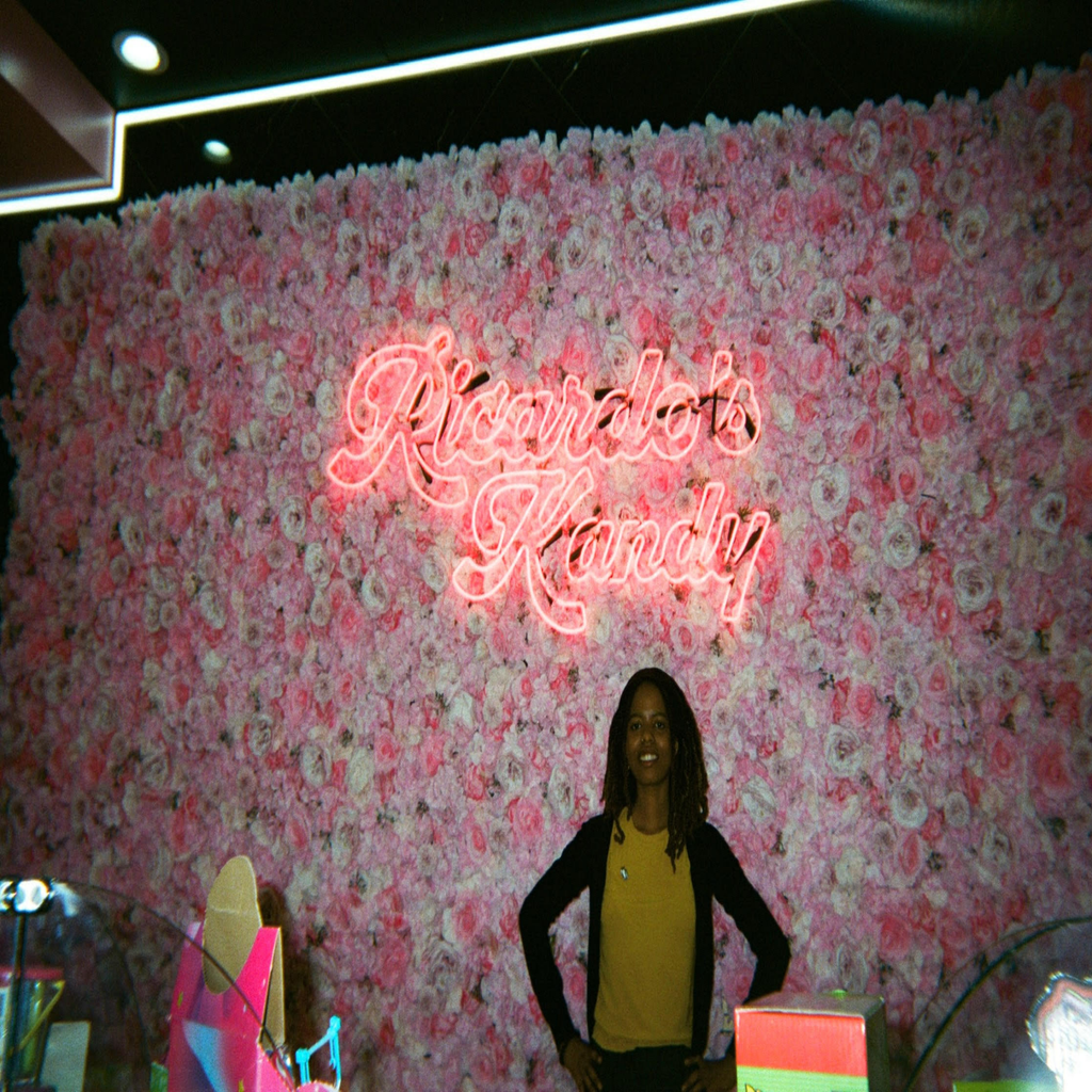 Black woman smiling infront of flower wall