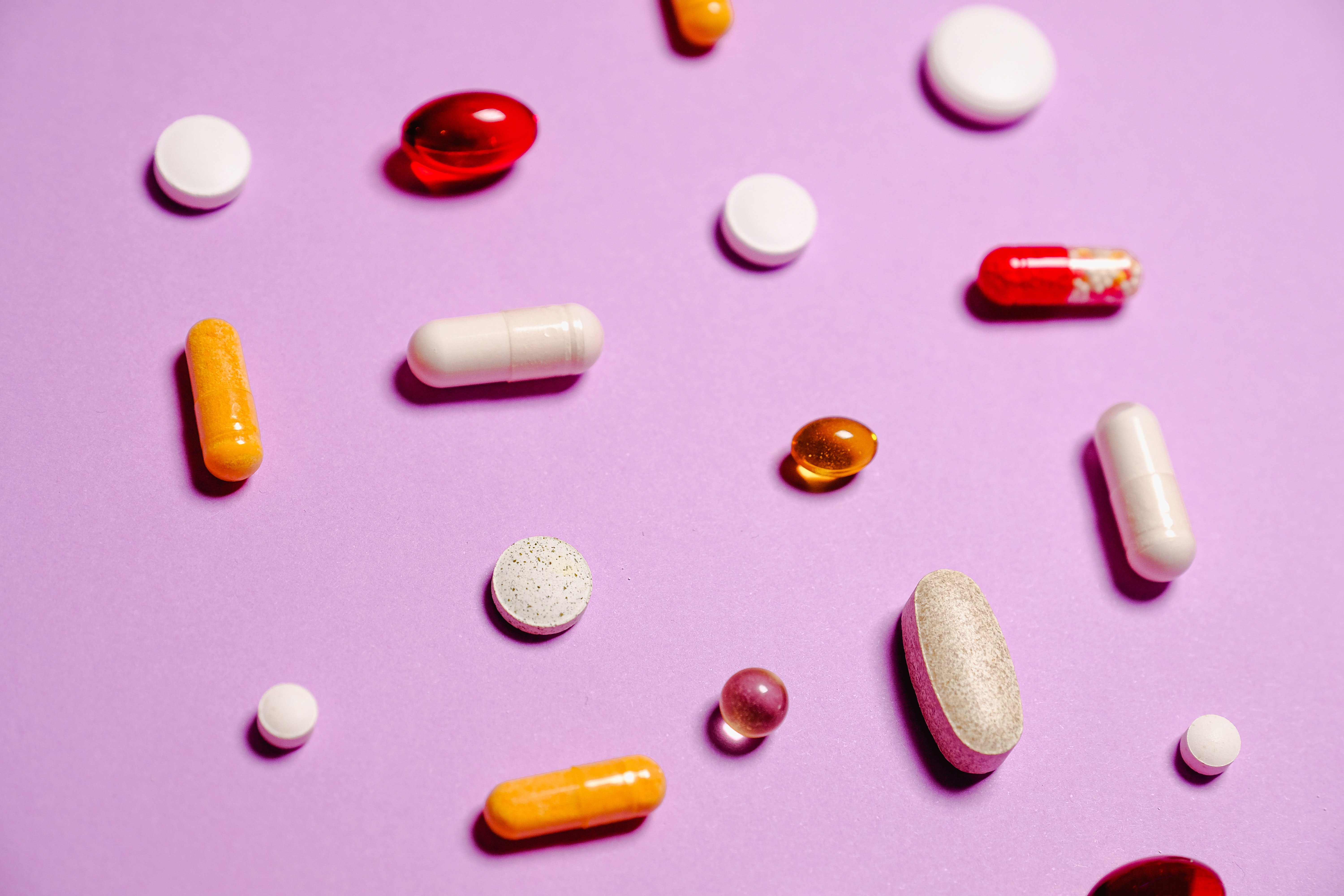 Vitamins laying on a pink background