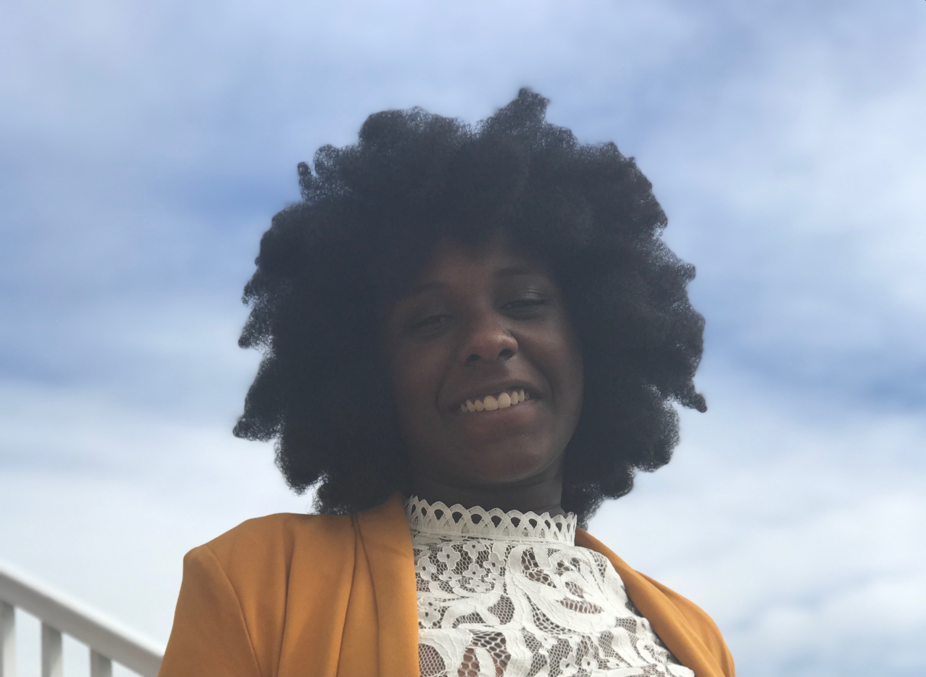 Girl with white shirt and yellow blazer with a blue sky for background.
