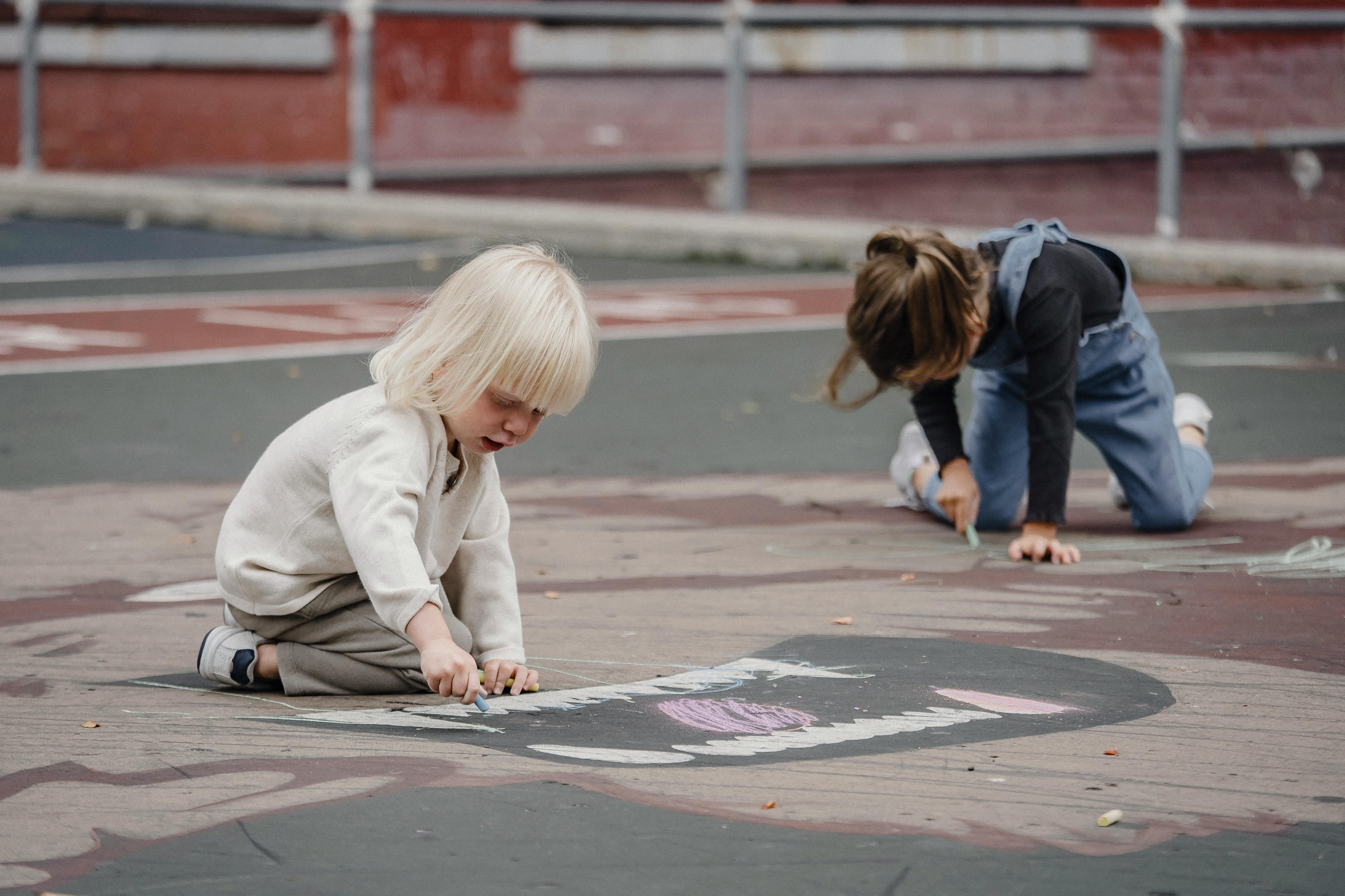 Little girls on asphalt with chalks