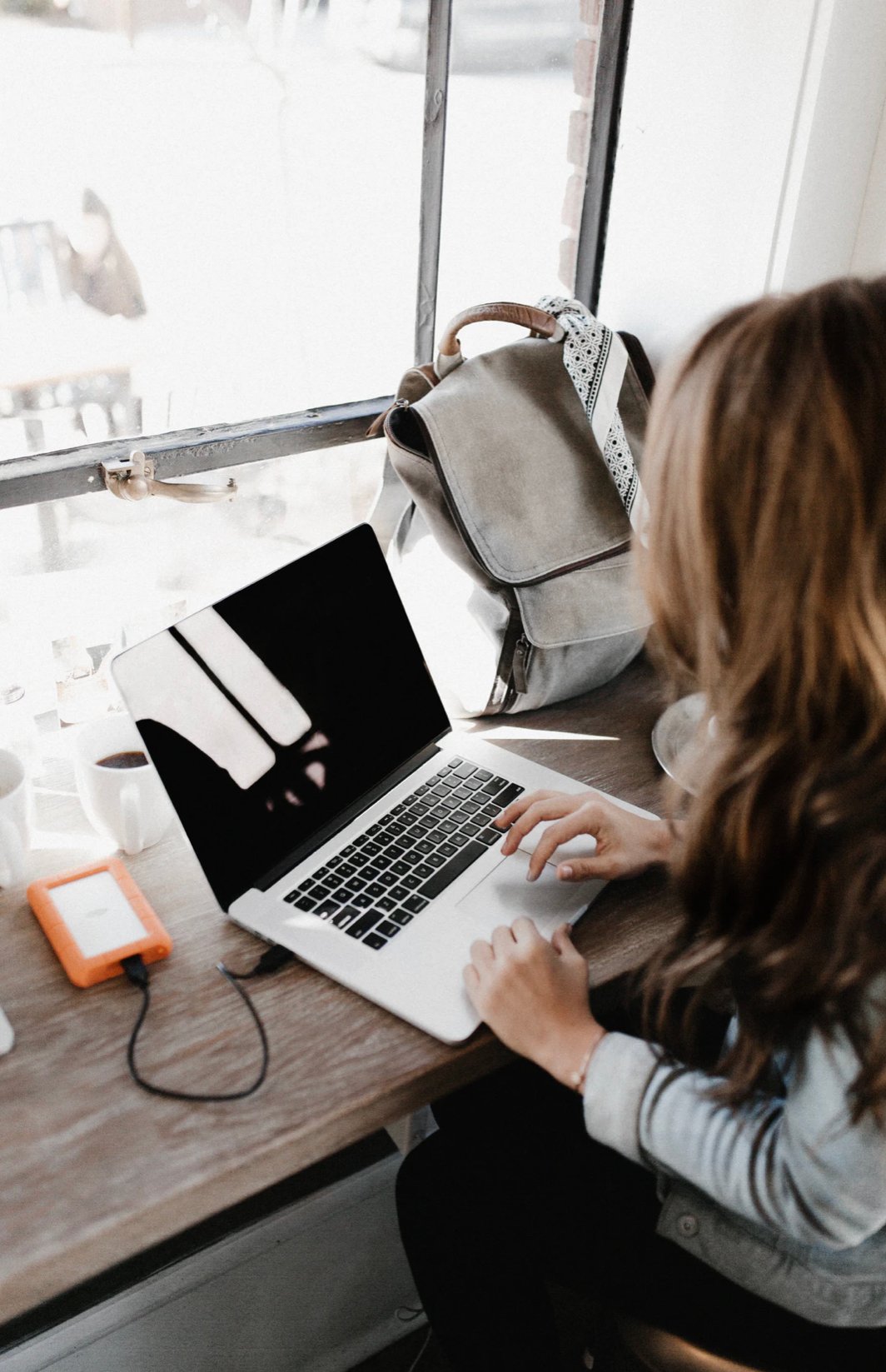 woman wearing gray long sleeve shirt working on a laptop