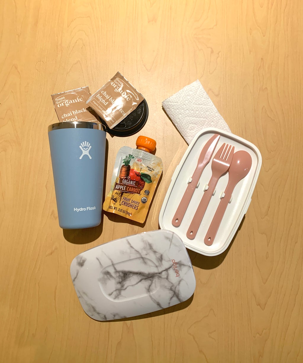 A water bottle, tea bags, bento box and apple sauce squeeze.