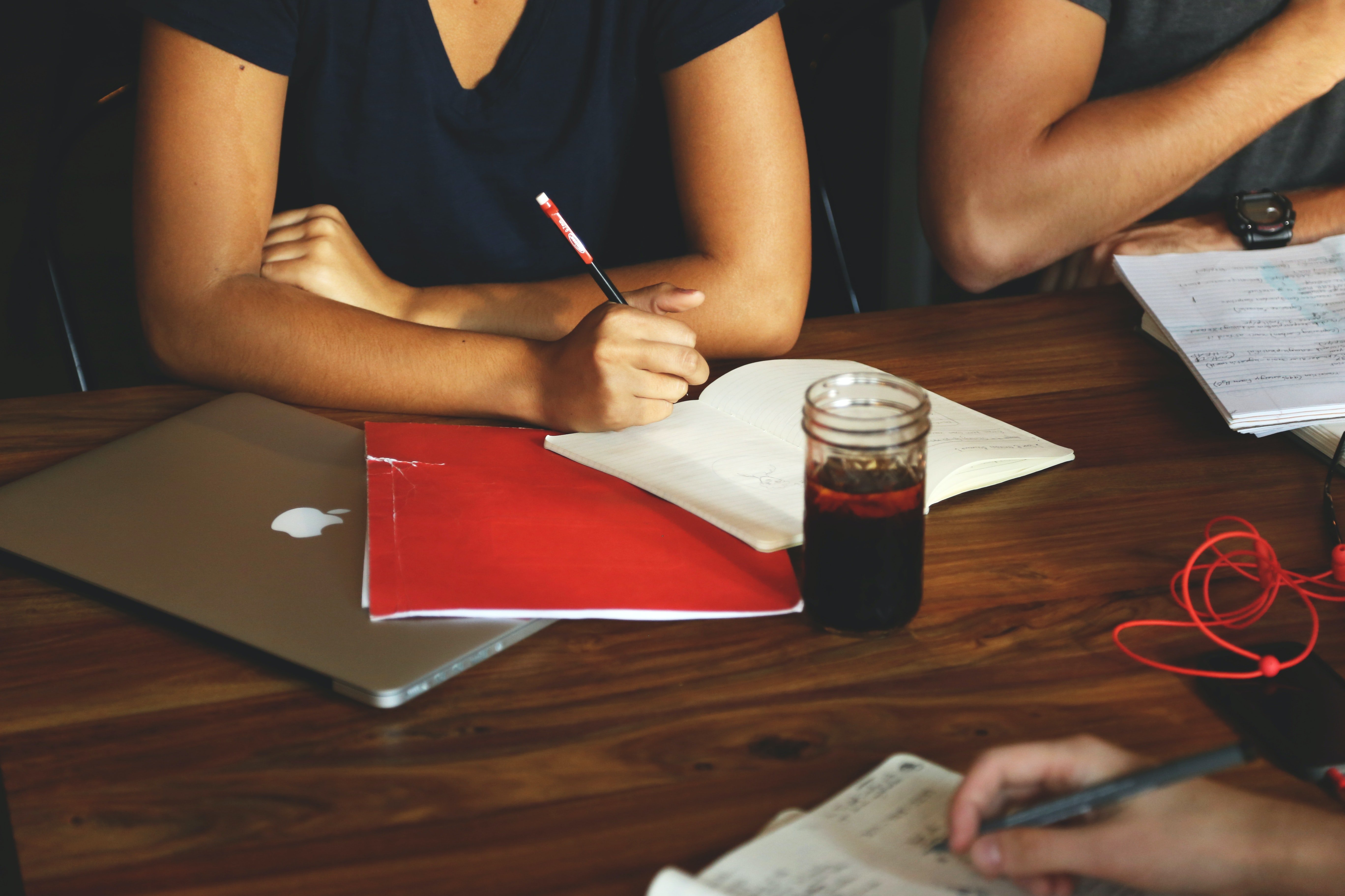people writing in notebooks at a table