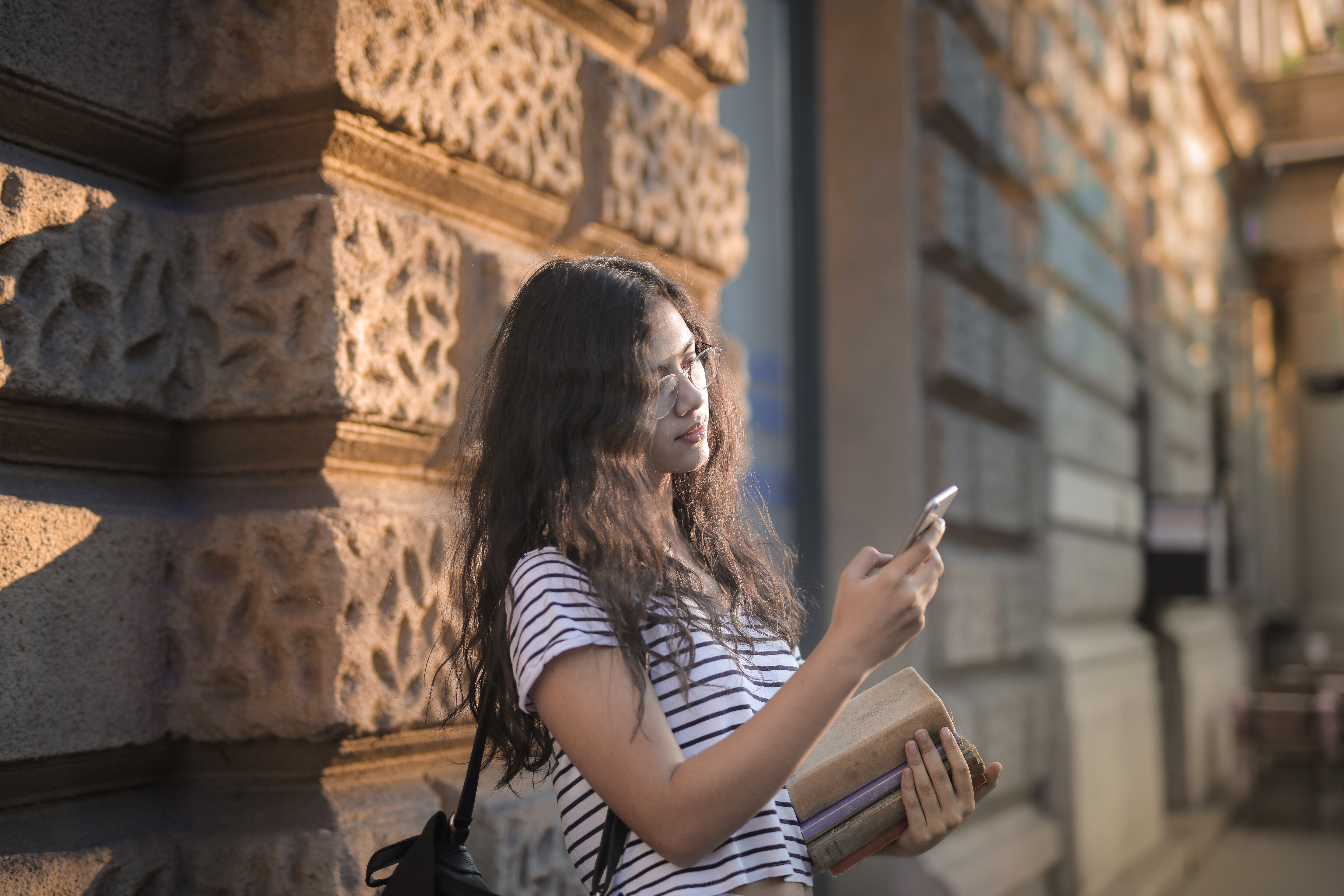 Girl on phone against college campus brick wall
