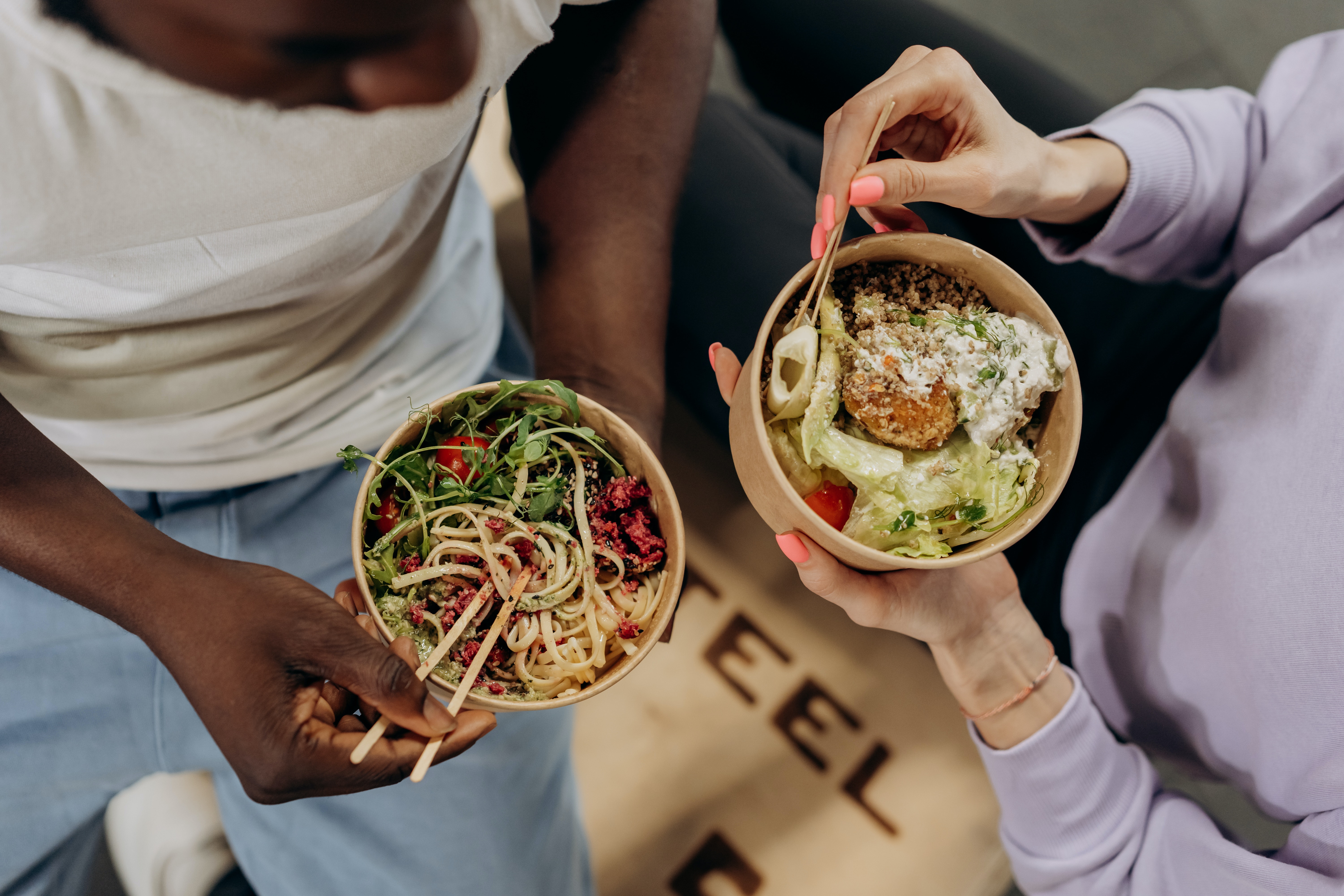 Two women hold bowls of food.