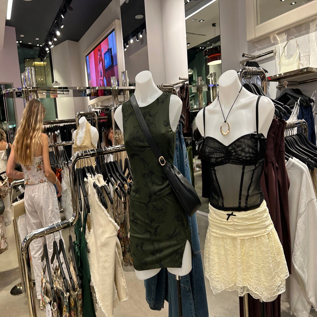 Two mannequins stand in a store of women\'s clothing.