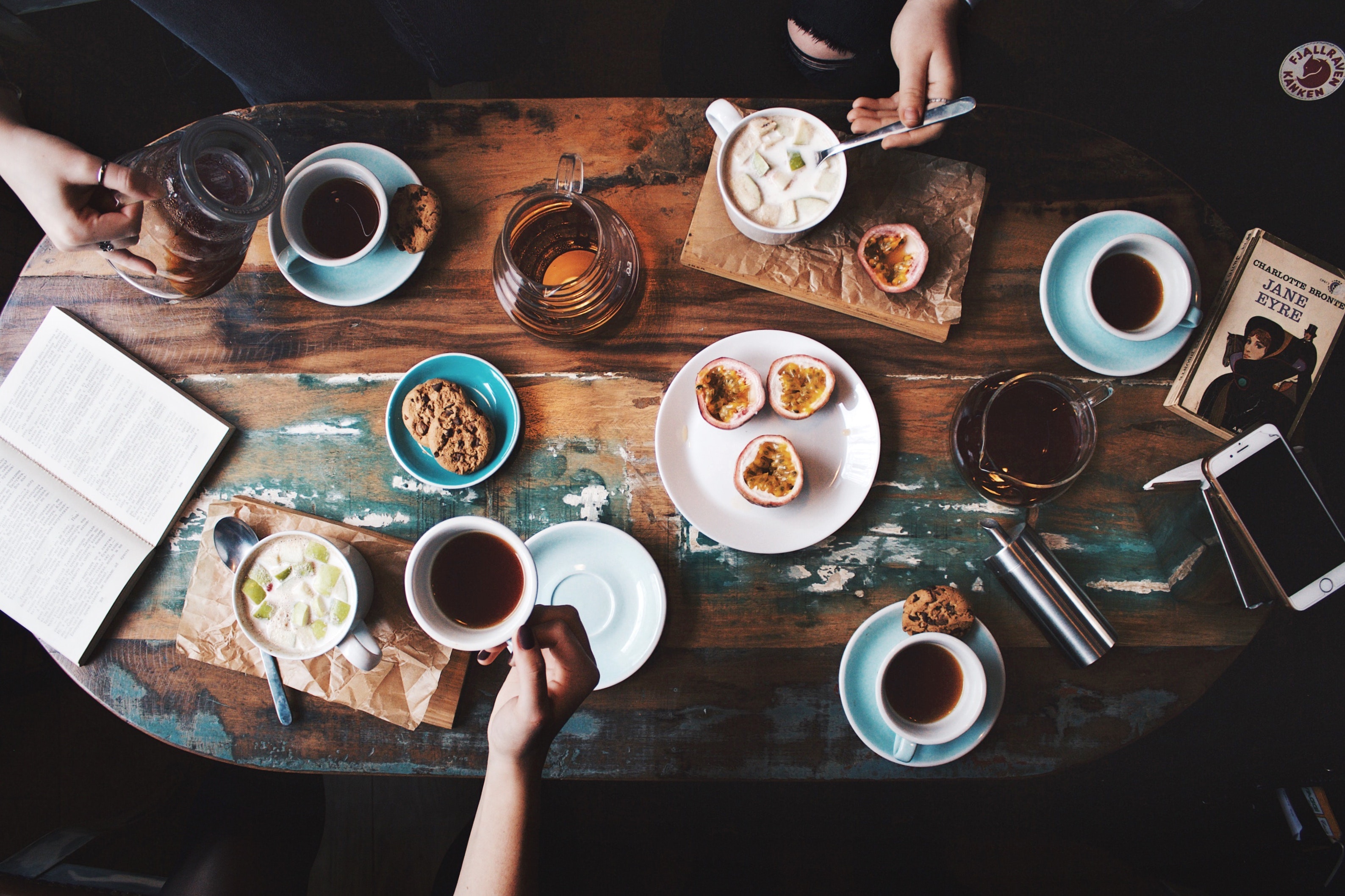 group of people in a coffee shop with food, drinks, and books