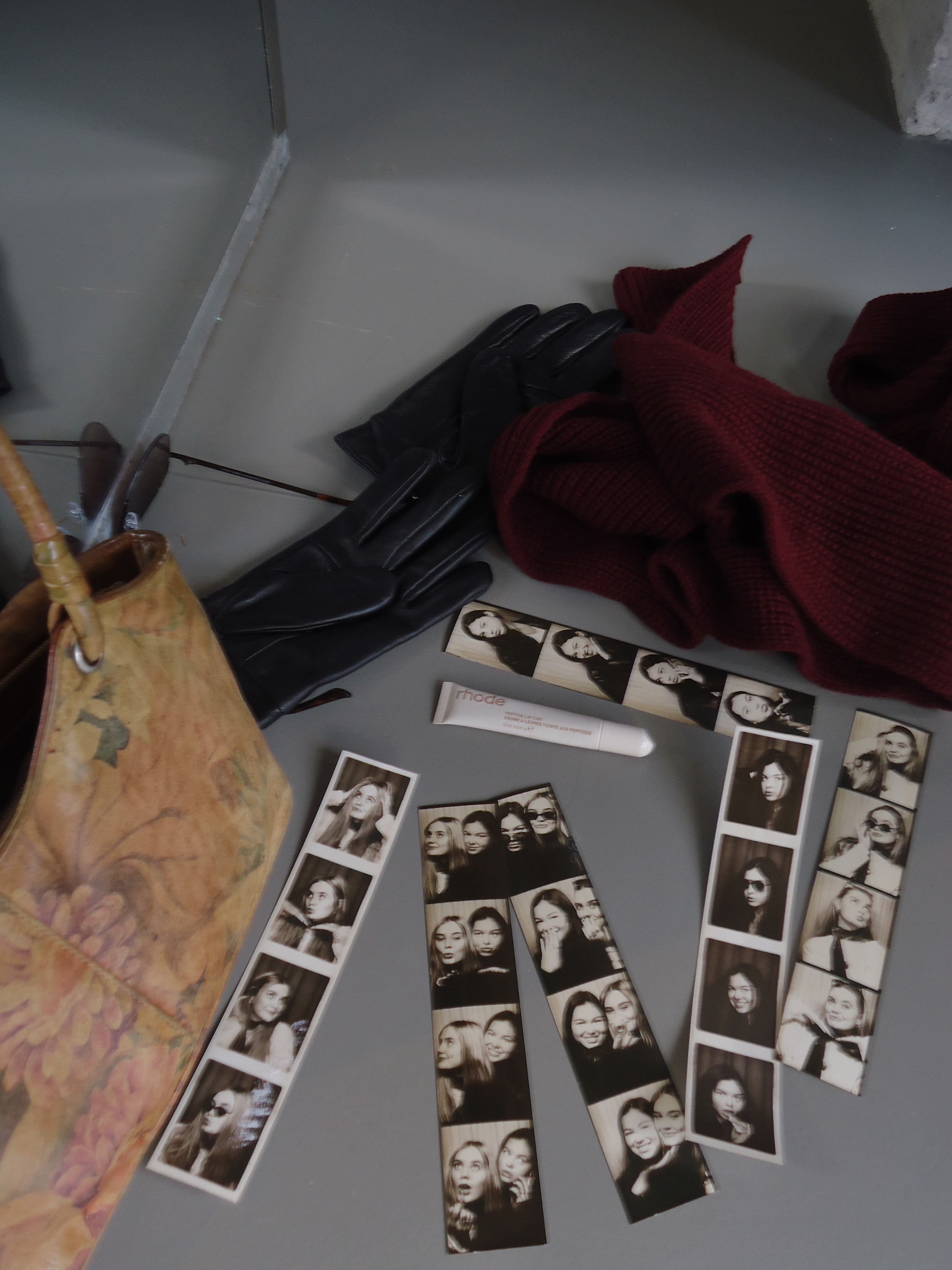 pile of photo booth strips of two friends and a purse and chapstick in frame