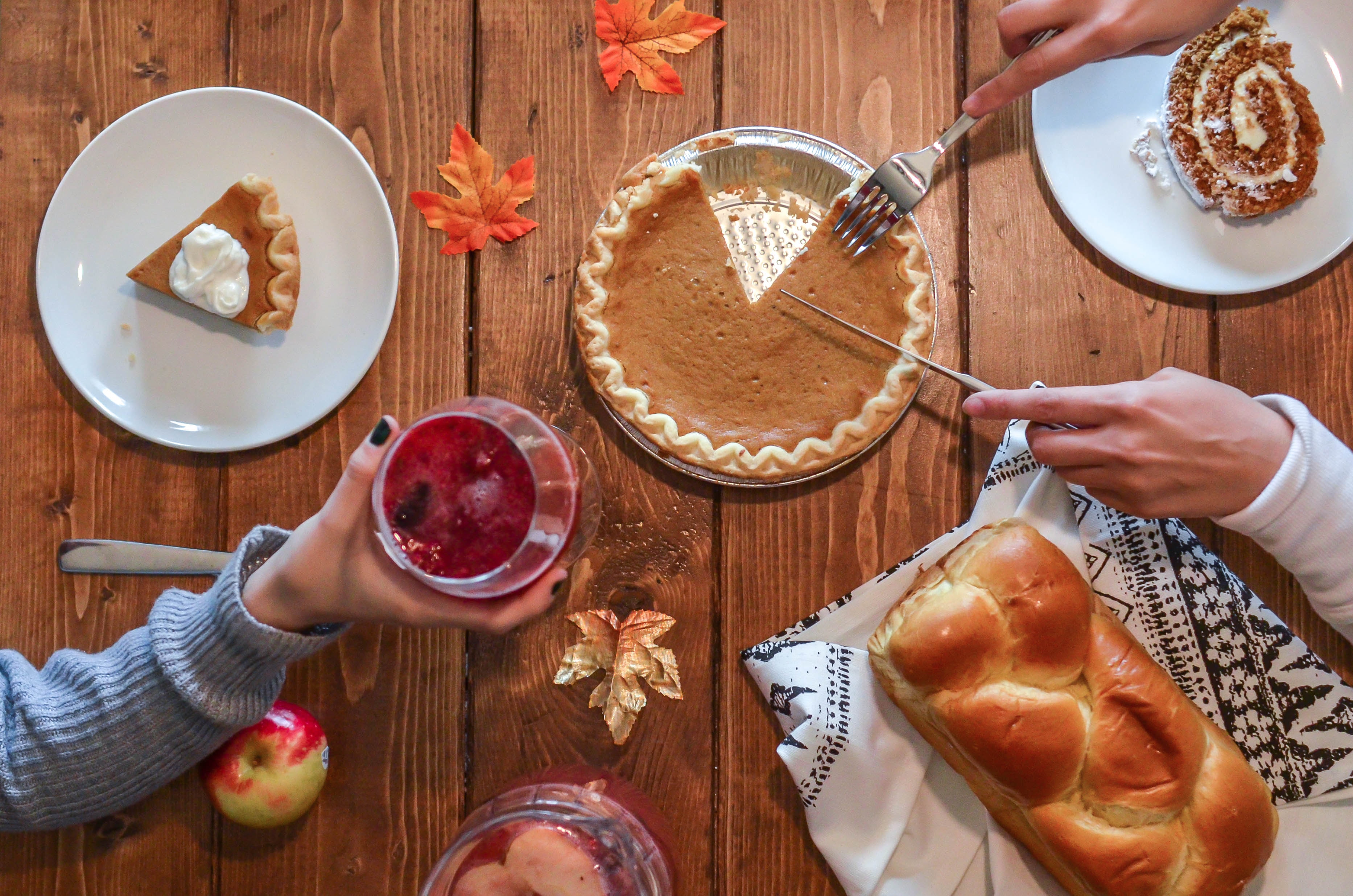 person slicing pie besides bread