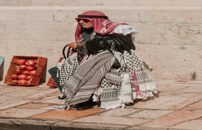 Man holding a variety of kuffiyeh scarves on his wrist.
