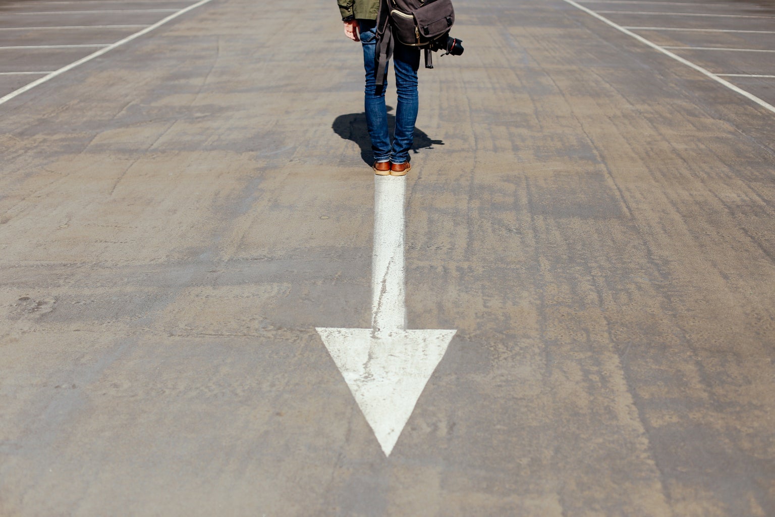 person standing on arrow sign on road photo