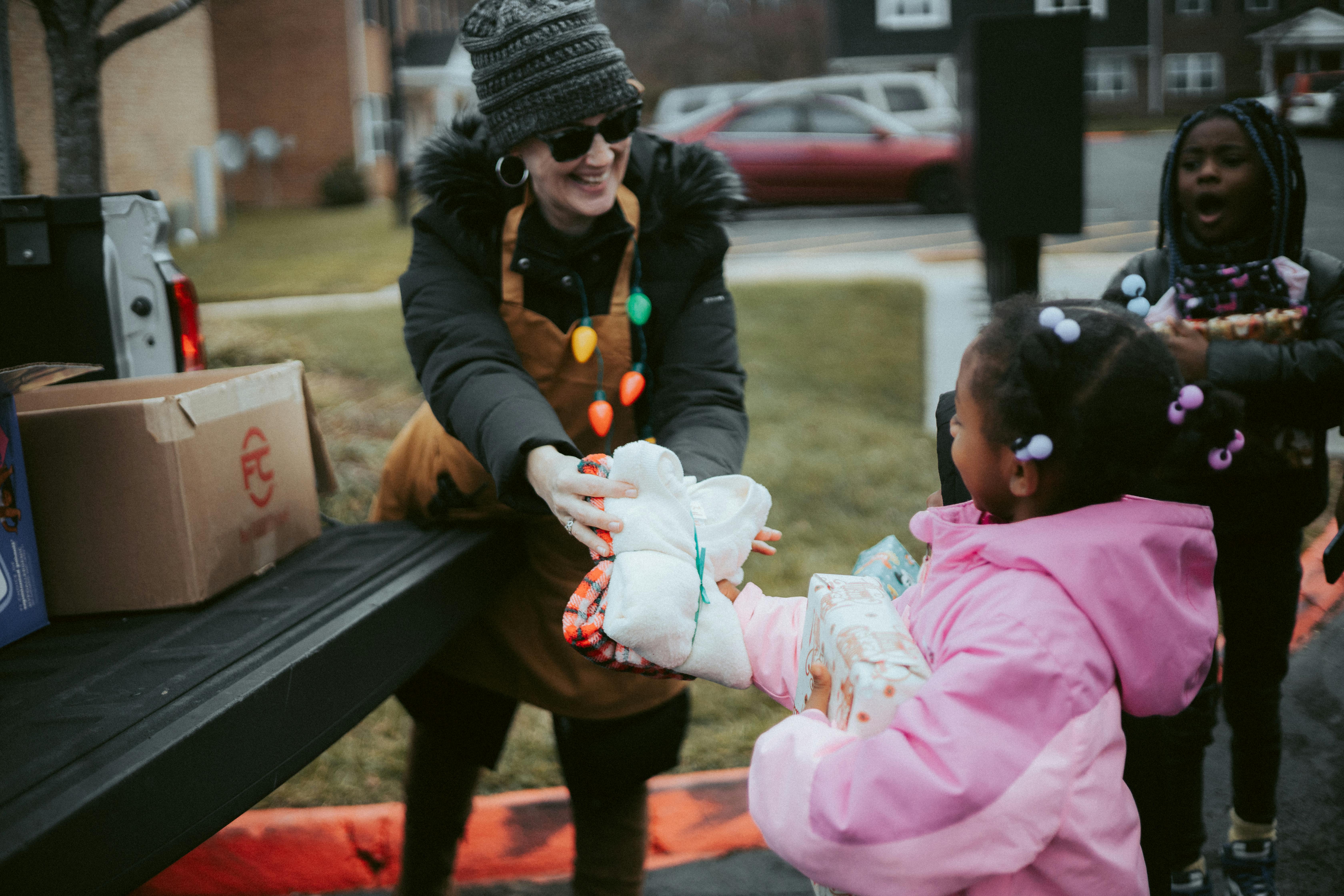 Lady giving clothes to a young girl.