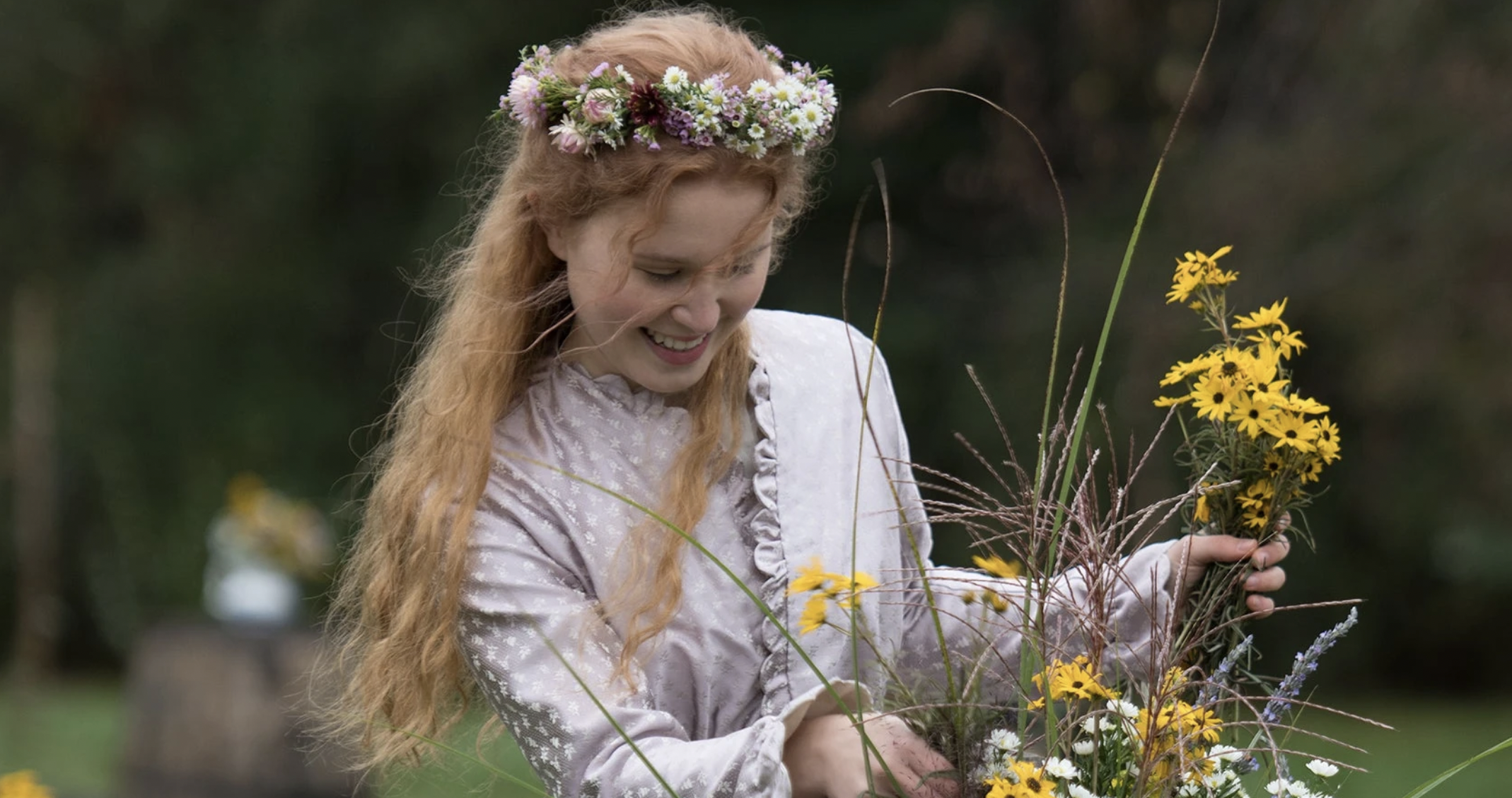 Girl smiling outside while holding various flowers and looking down