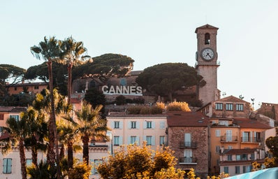 A natural landscape of Cannes in France. There is a clock and trees in the picture too.