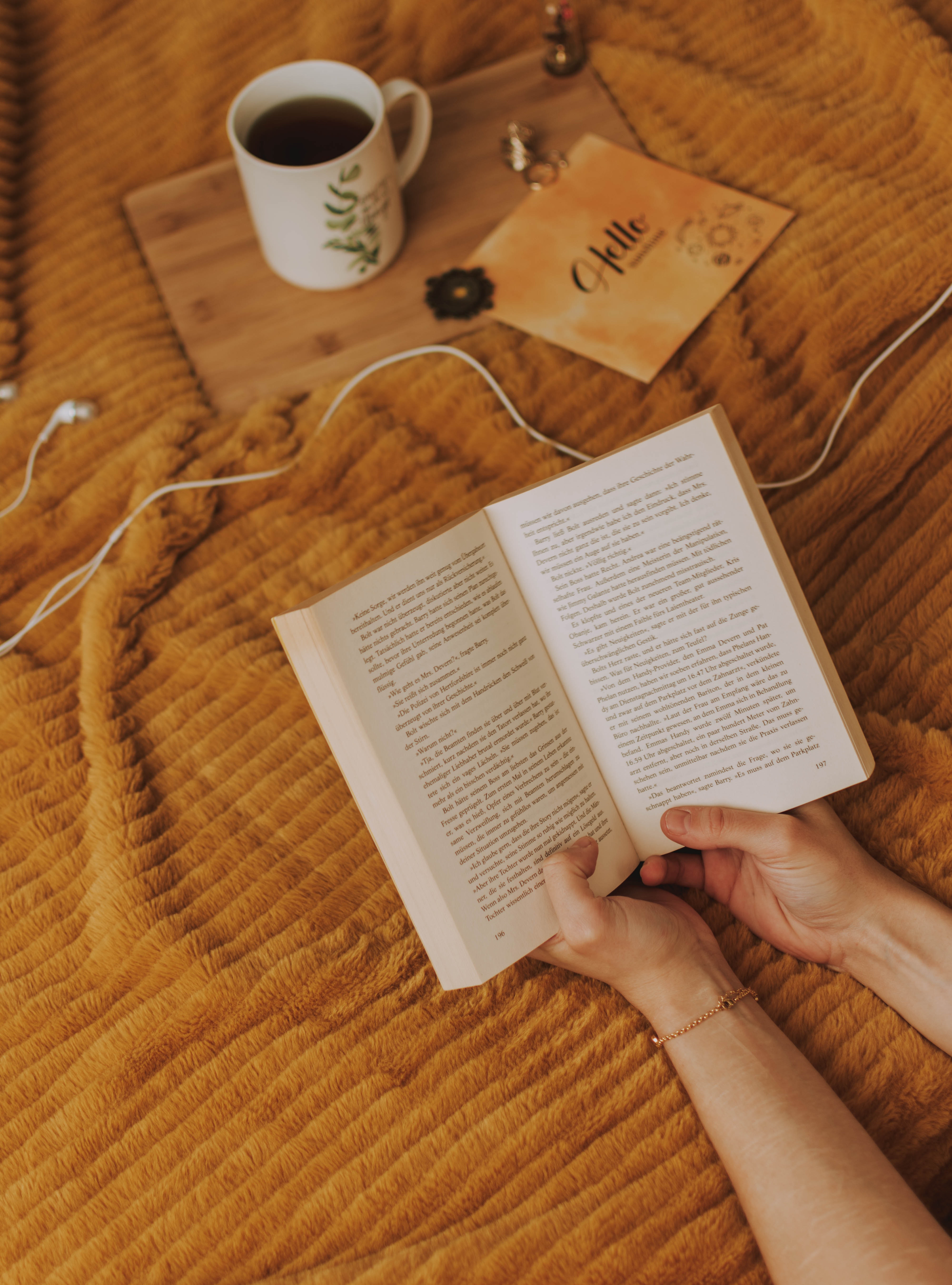 Someone holding a book on a yellow bed.