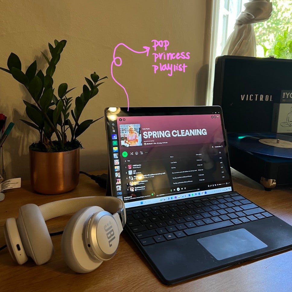 computer with spotify playlist open and headphones on a desk