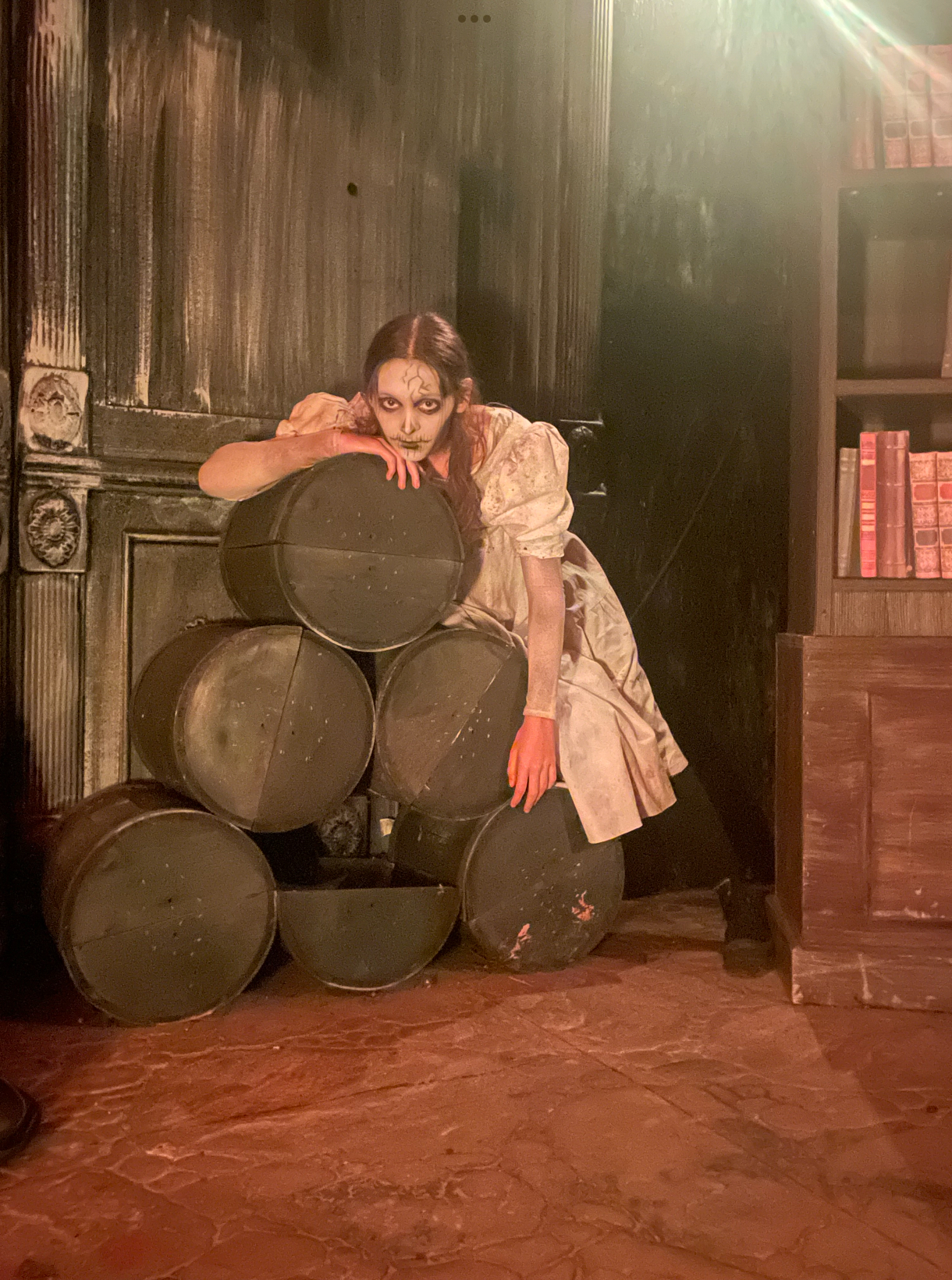 A scare actor with skeleton makeup leaning on a stack of barrels