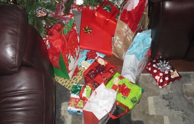 A pile of Christmas gifts under a Christmas tree.
