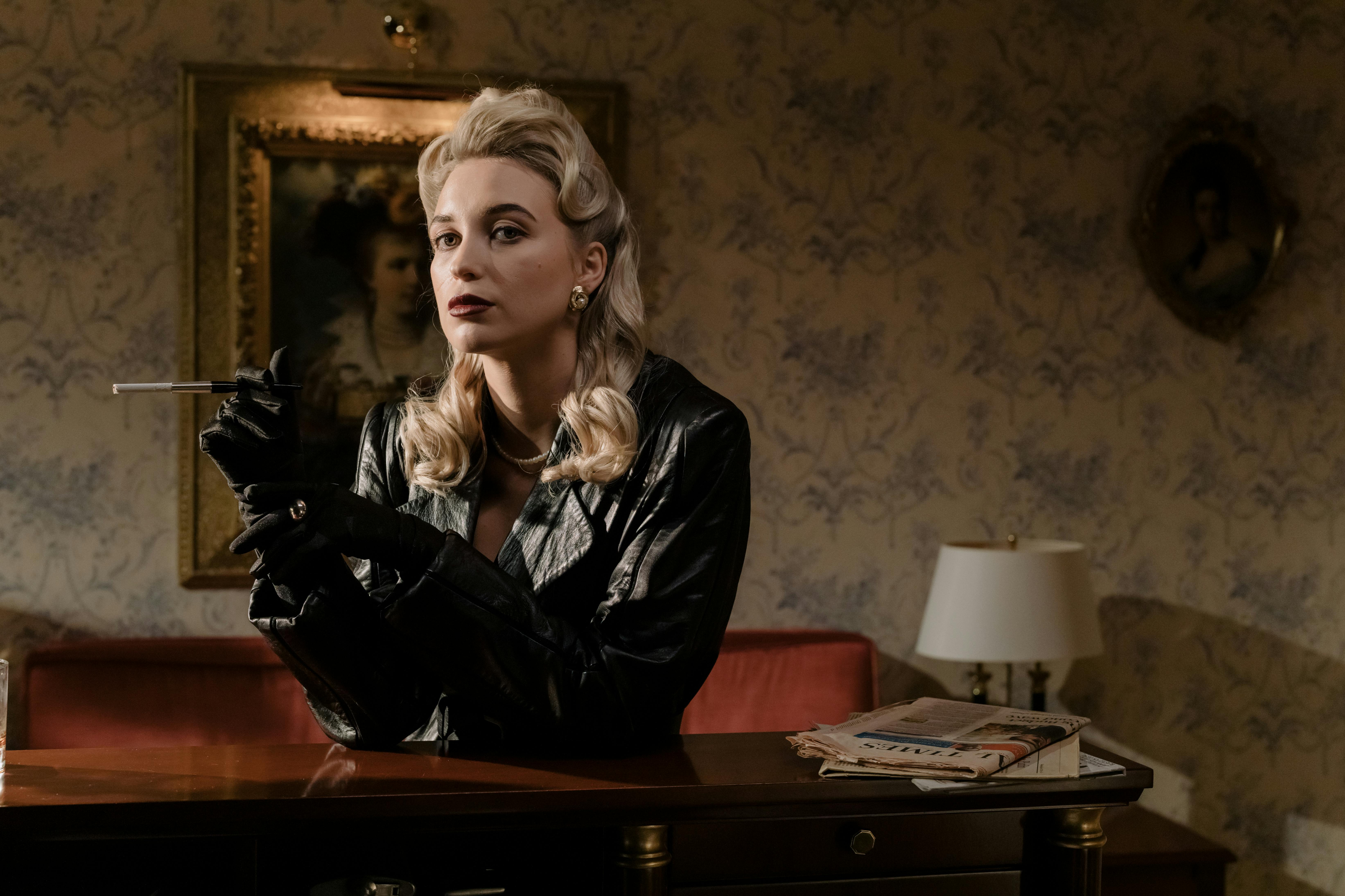 Blonde woman in black leather coat holding a cigarette