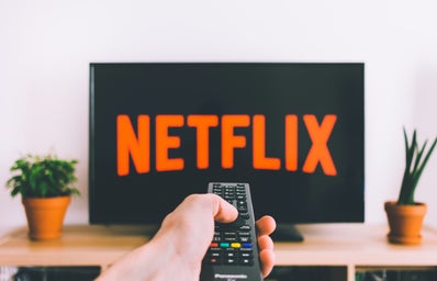 hand holding remote with Netflix on TV screen