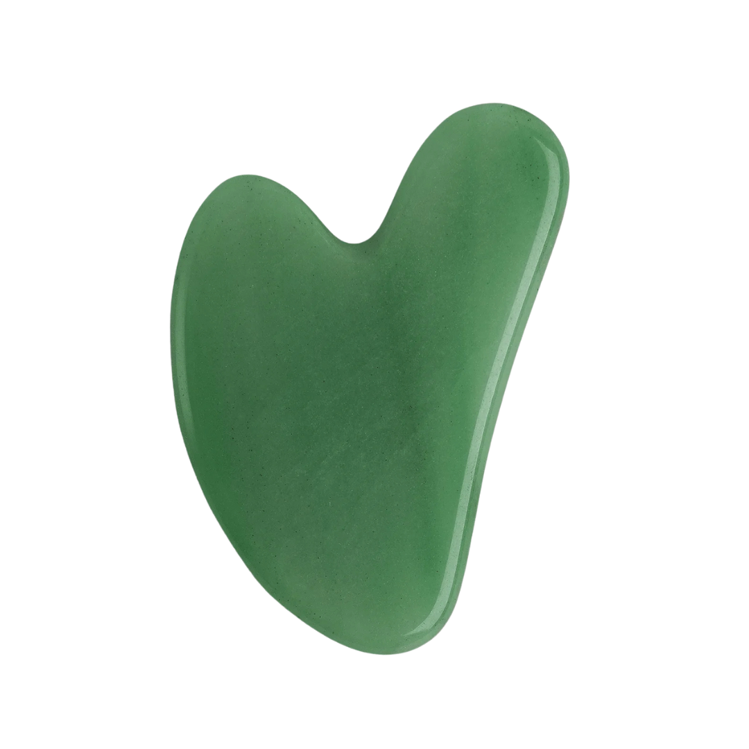 Heart-shaped green jade gua sha tool against a white background. The smooth, curved stone conveys a sense of calm and relaxation.