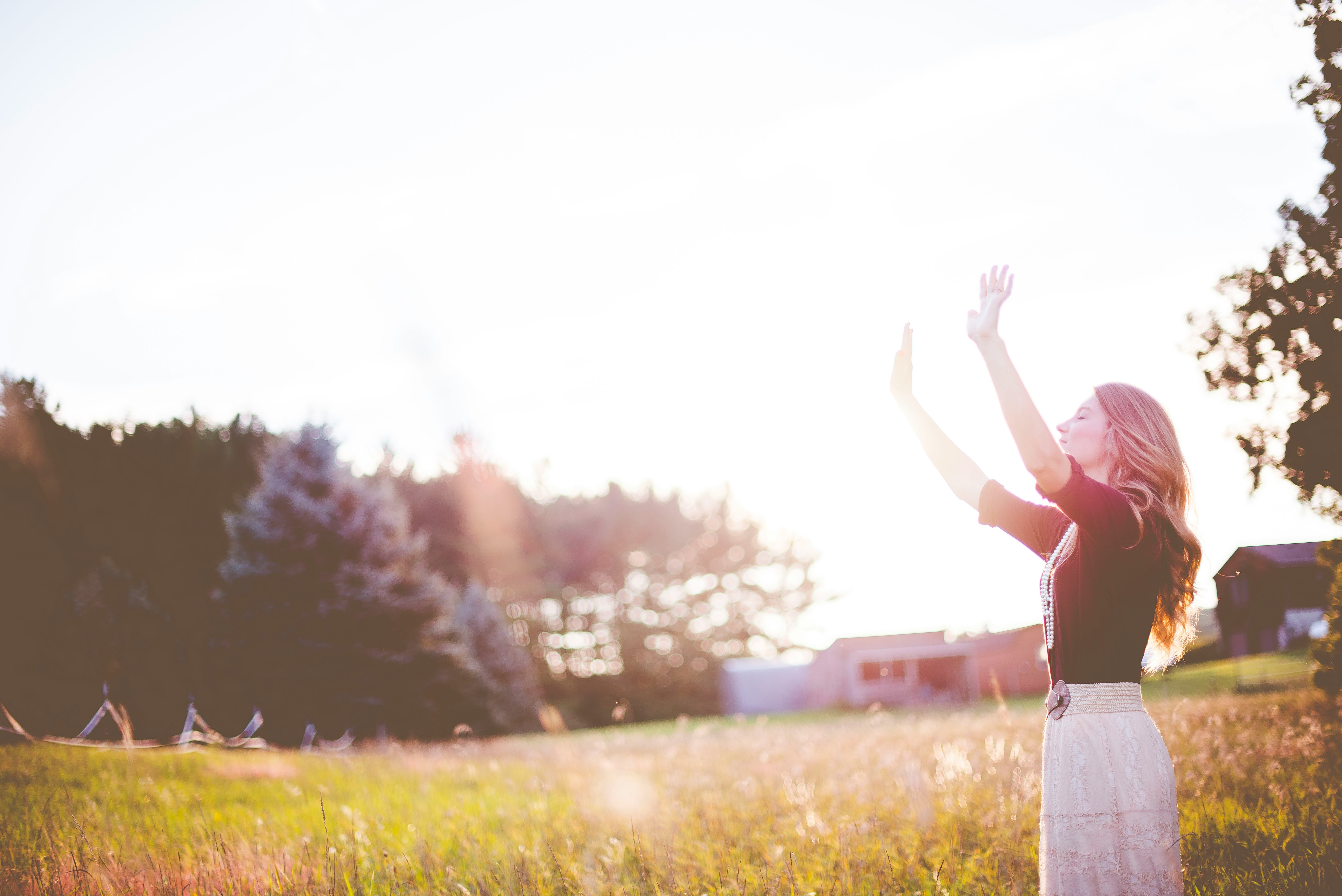 Woman with hands up in front of greenhouse