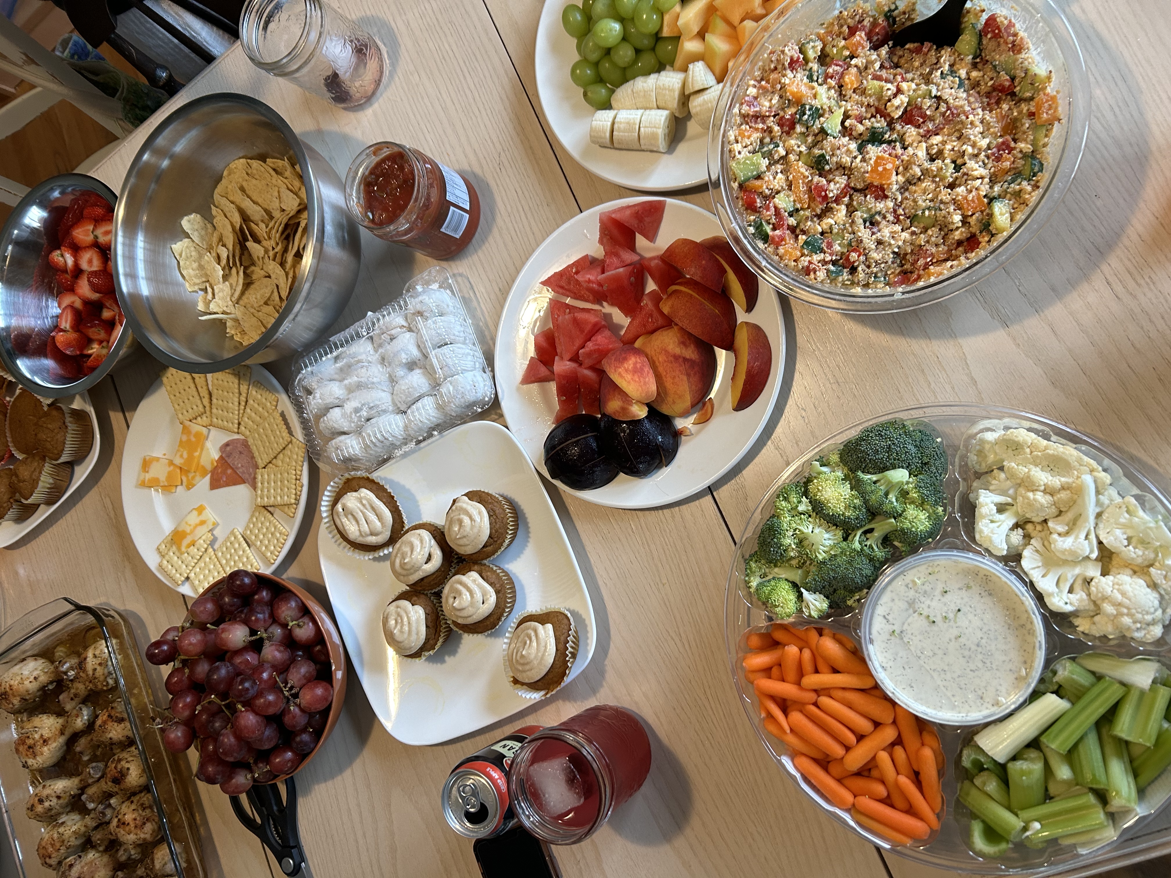 overlay of table of food items like veggies, desserts, grapes, chips and mroe