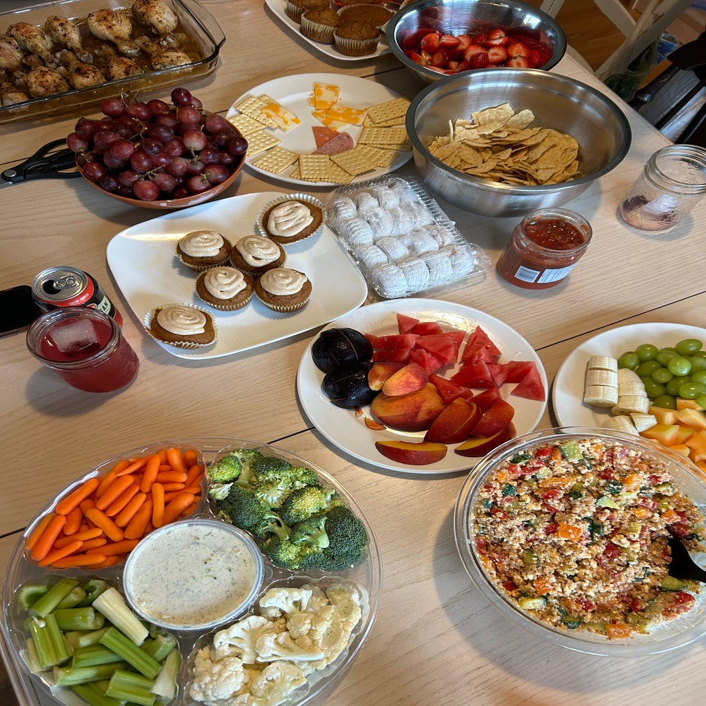 overlay of table of food items like veggies, desserts, grapes, chips and mroe