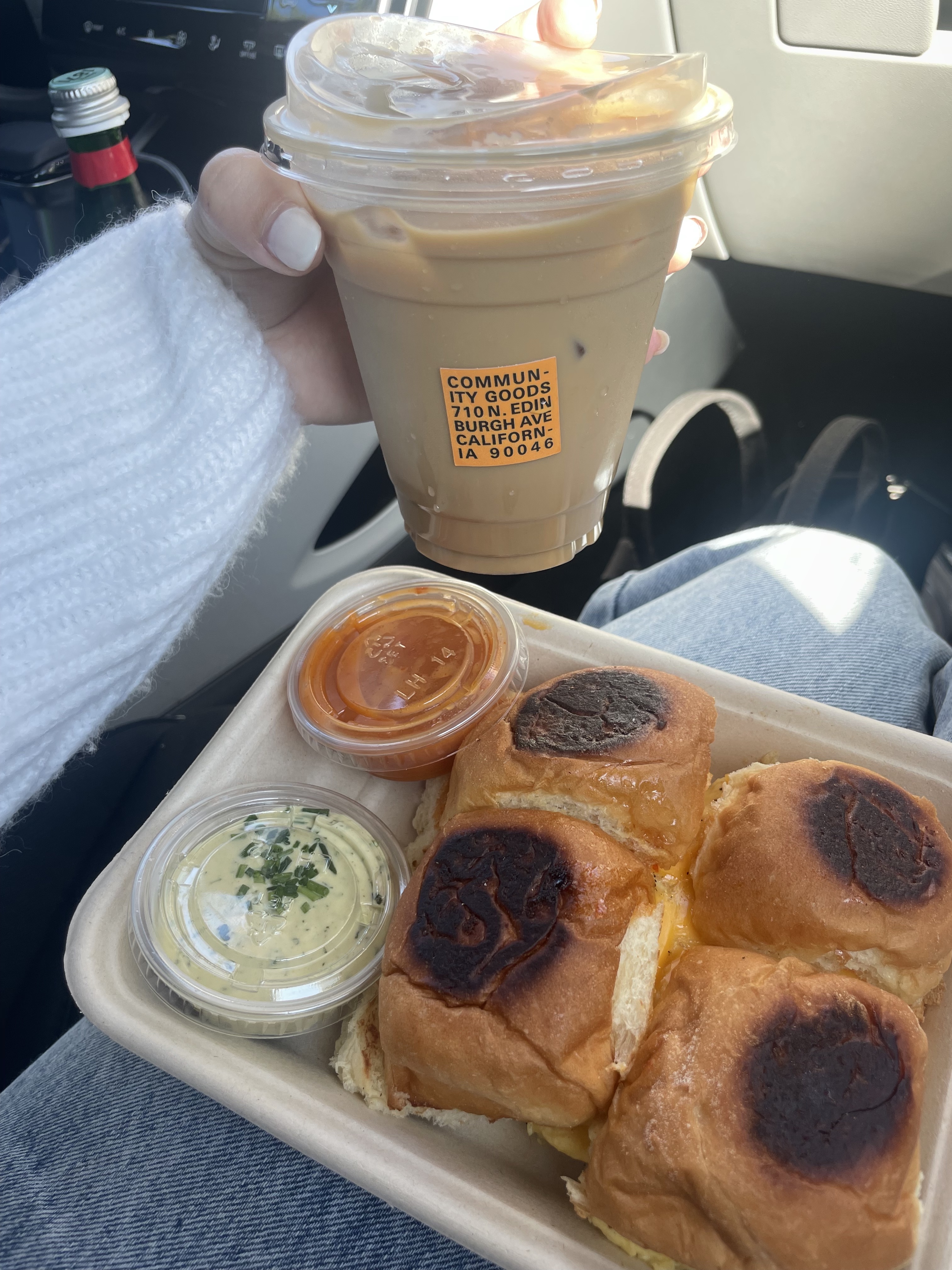 holding coffee cup and breakfast egg sandwiches