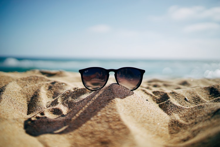 ray bans on sandjpg by Unsplash