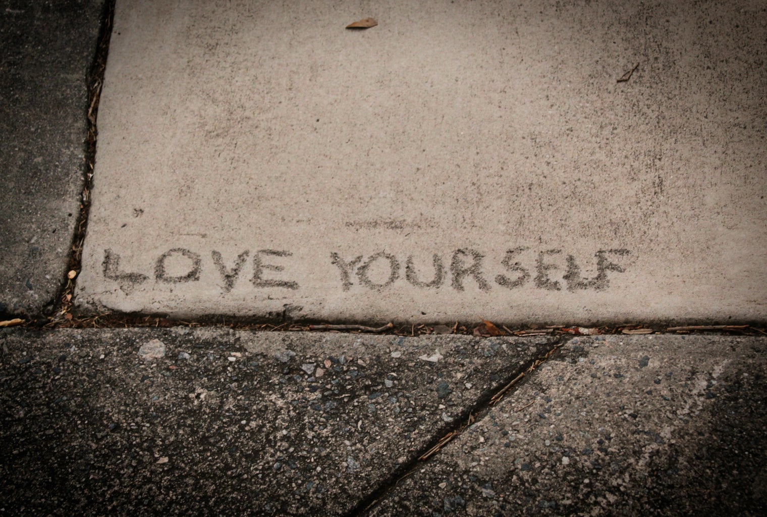 love yourself written on a sidewalk