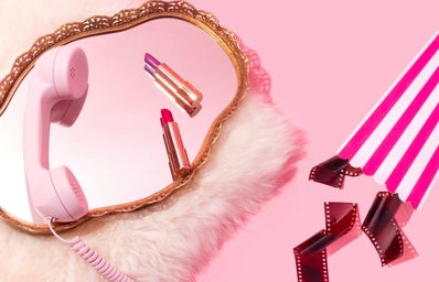pink background, fuzzy rug with mirror and cable phone, lipsticks, popcorn box and film reels