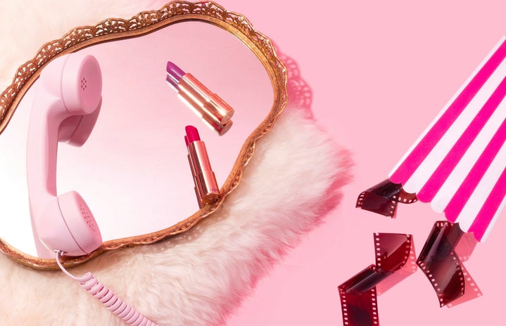 pink background, fuzzy rug with mirror and cable phone, lipsticks, popcorn box and film reels