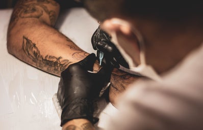 person tattooing arm