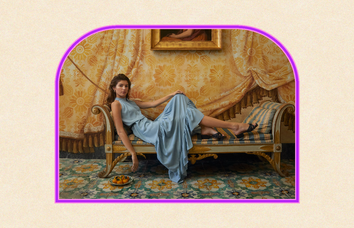 Woman wearing a long blue dress sitting on a chaise lounge