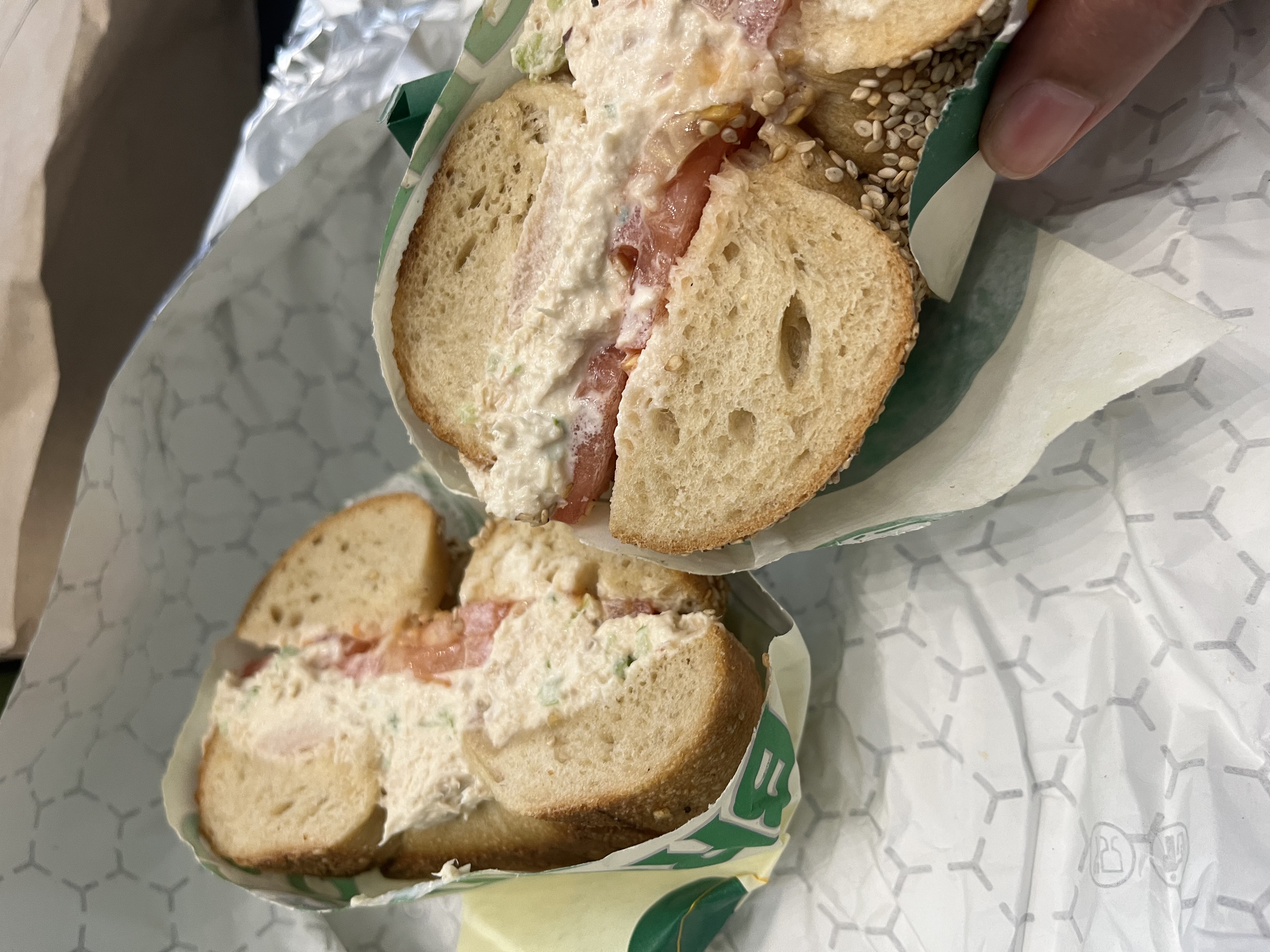 A sesame seed bagel with filling and tomato