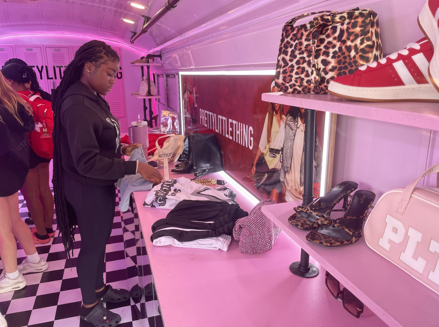Student looking at clothing and jewelry inside pink PrettyLittleThing pop-up bus