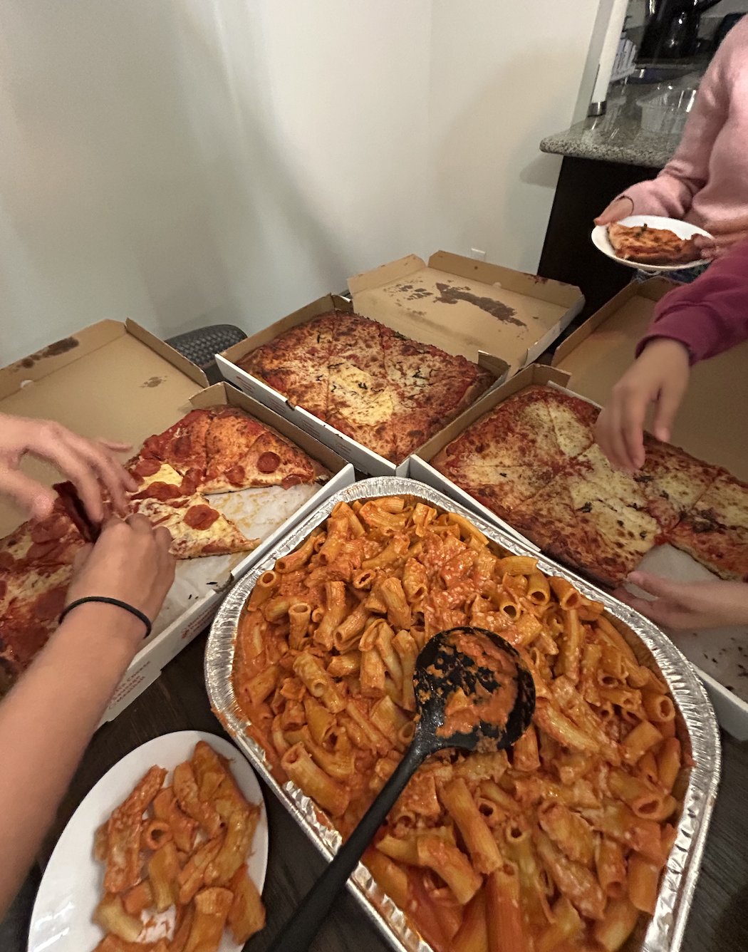Girls serving themselves pizza and pasta.