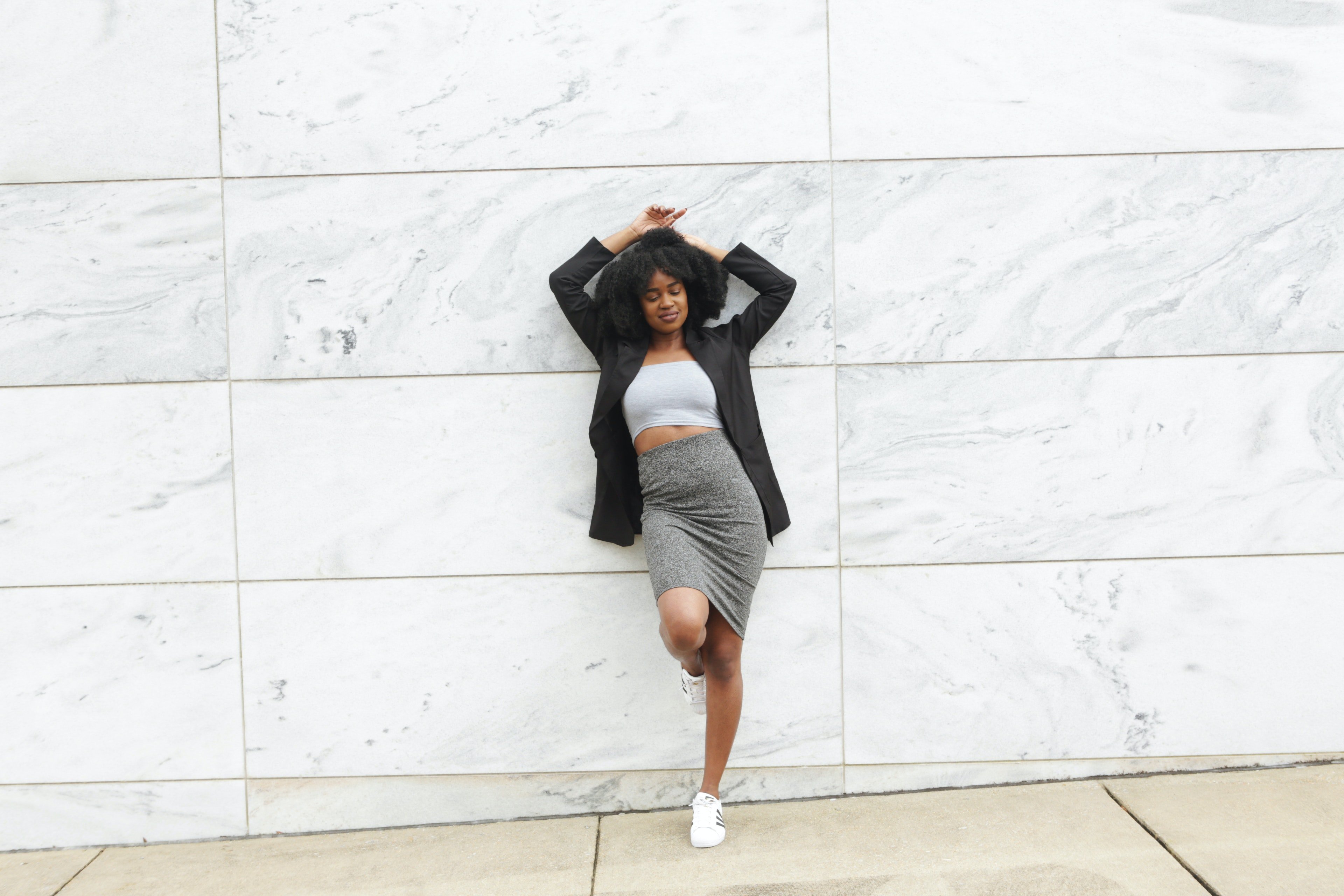 woman leaning up against building wall by Ogo