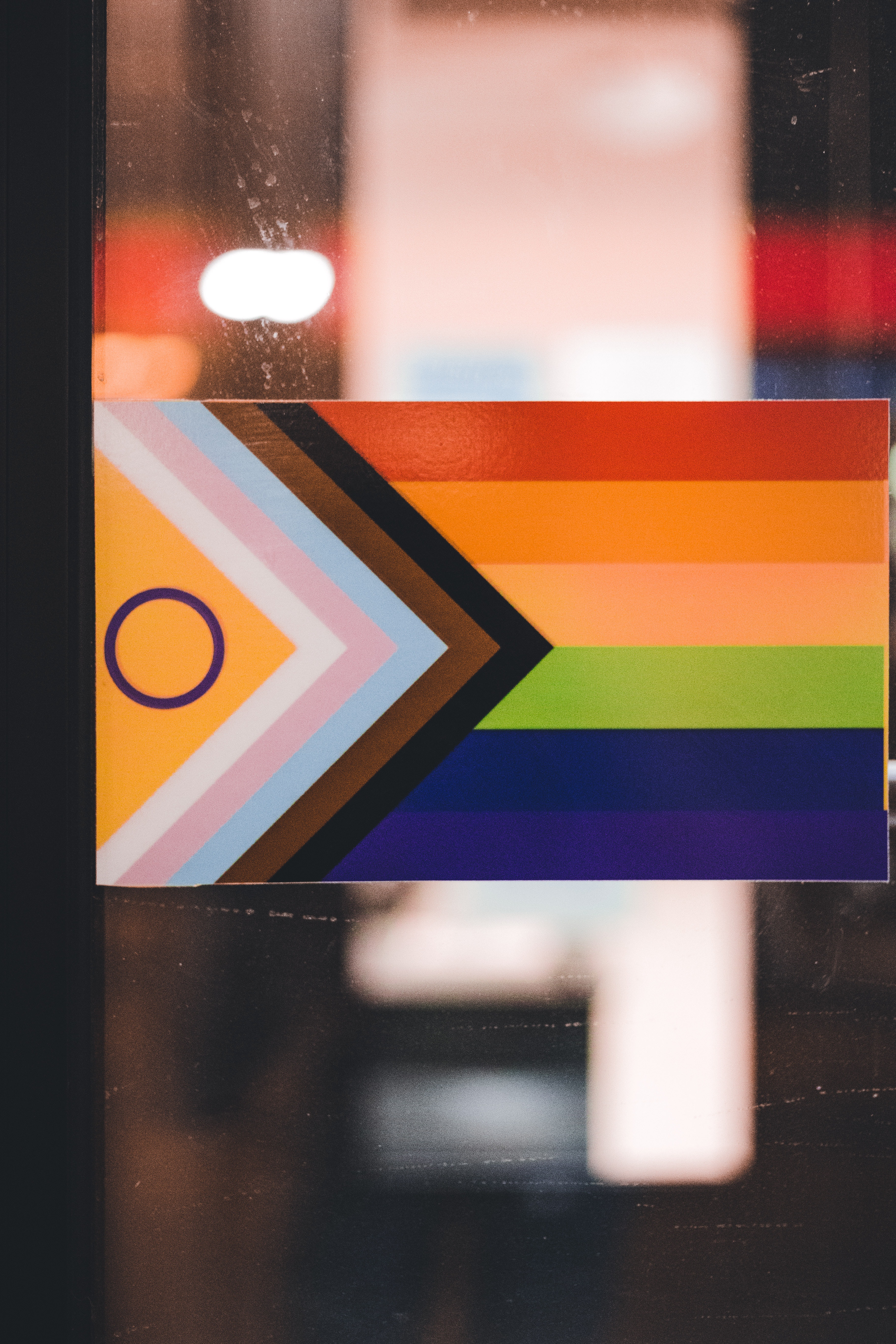 Progress pride flag in front of clear glass