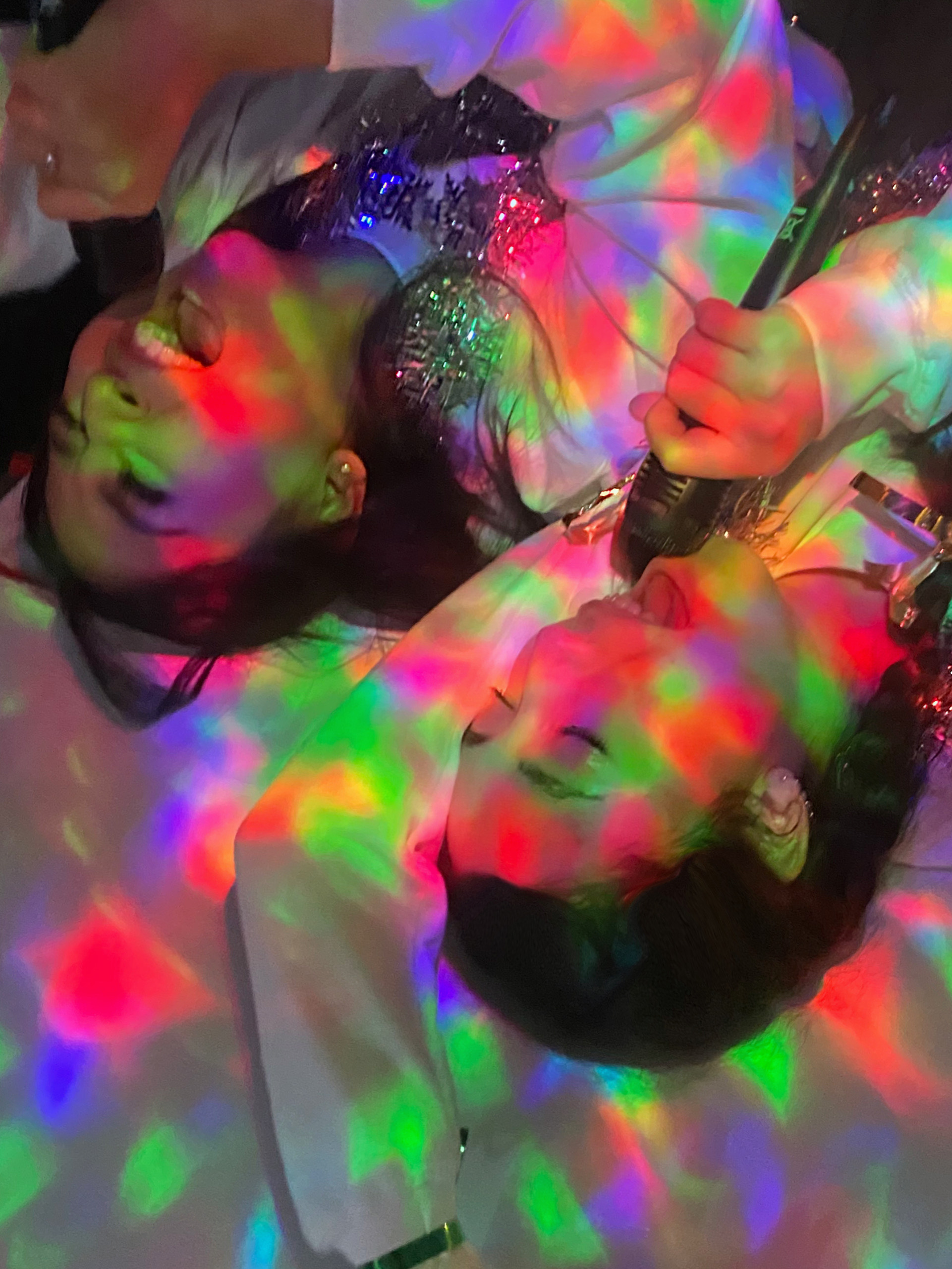 two girls singing into a microphone laying on a table