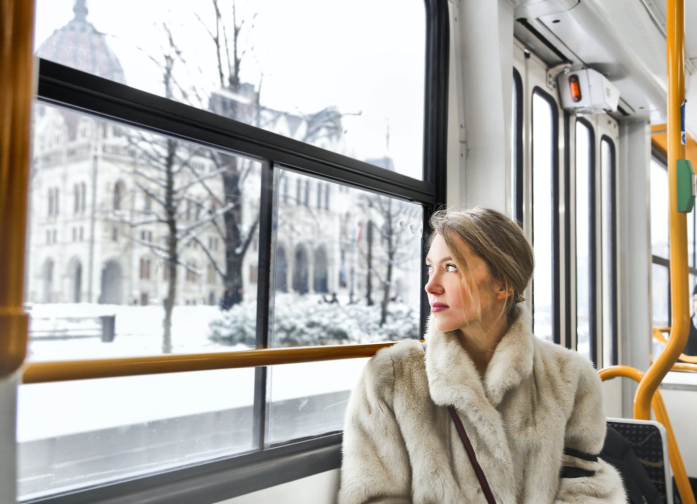 Woman looks out the bus window at the snow outside.