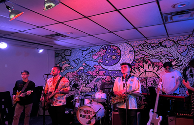 Band on stage with pink, purple coloring in background