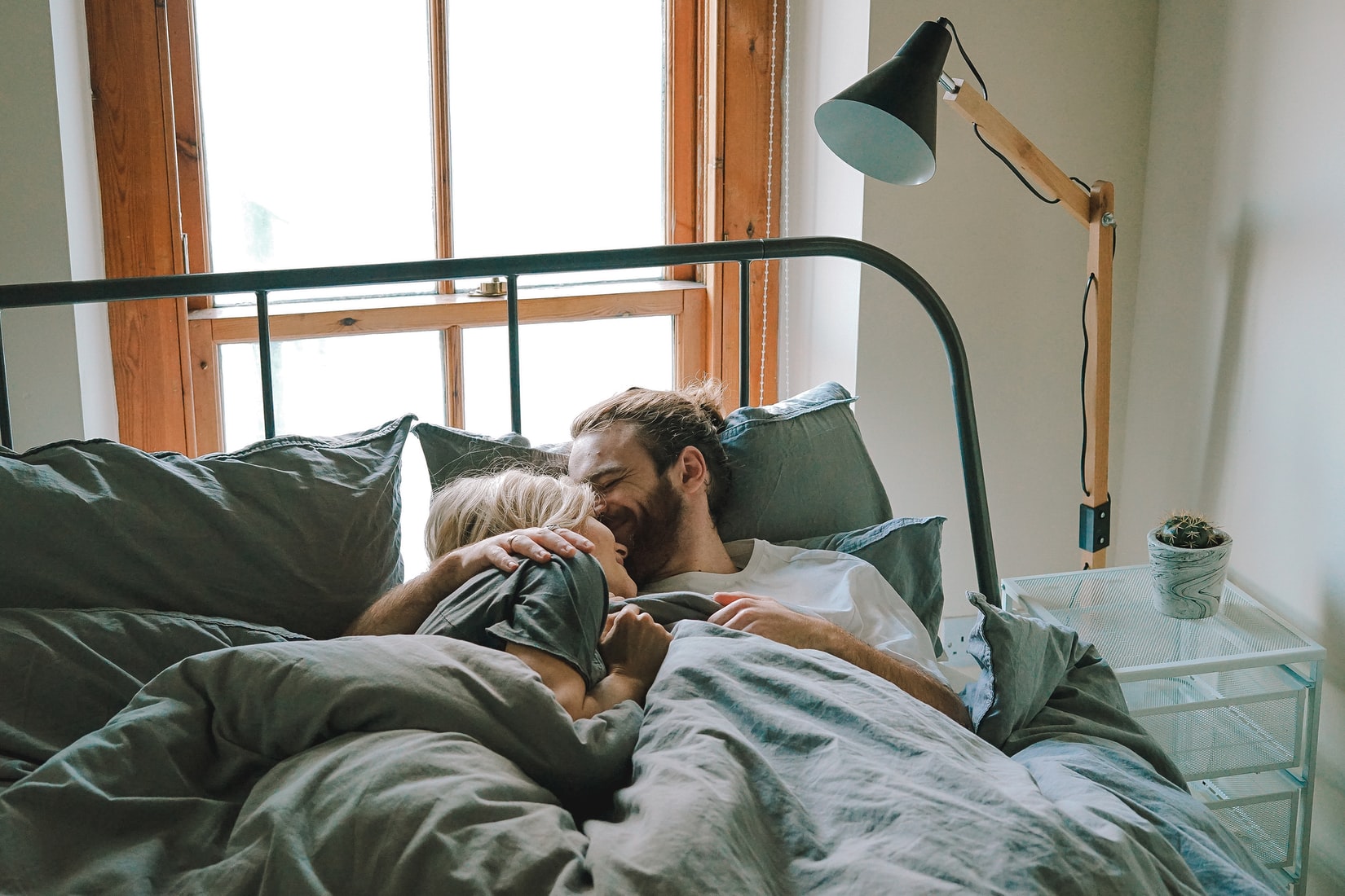 Couple kissing on forehead in bed