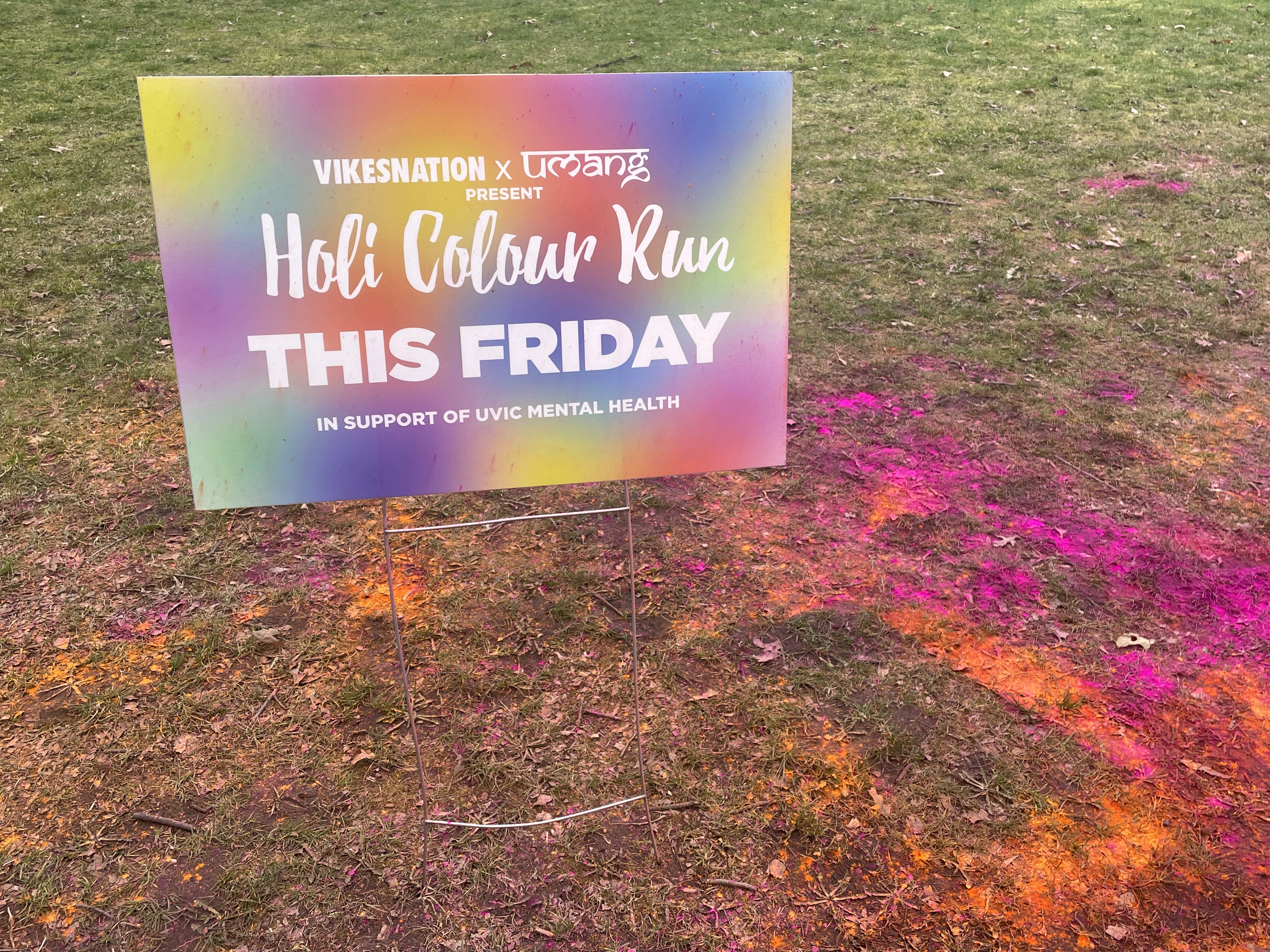 colourful powder on grass in front of orange holi sign
