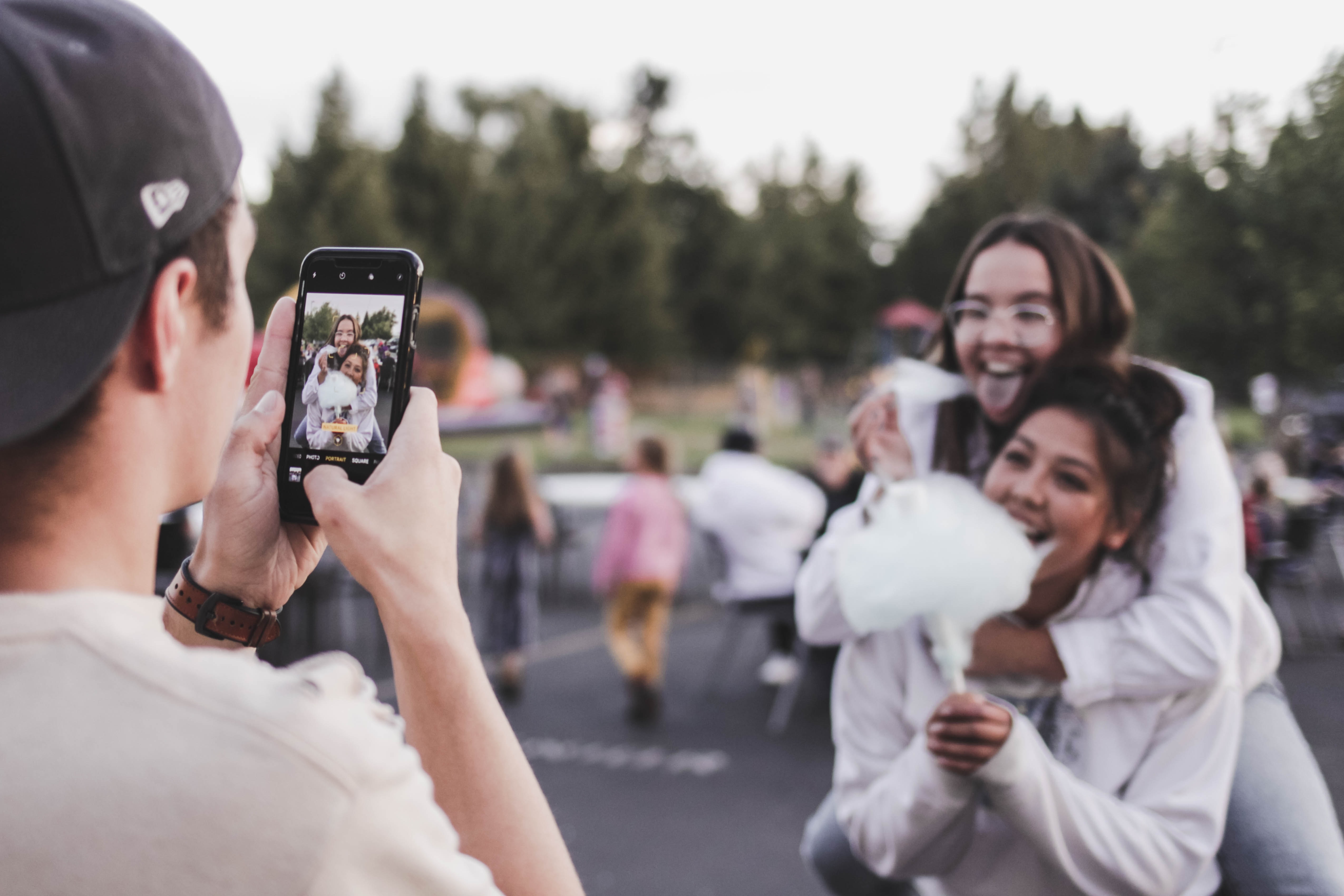 A man taking a photo of two women eating cotton candy