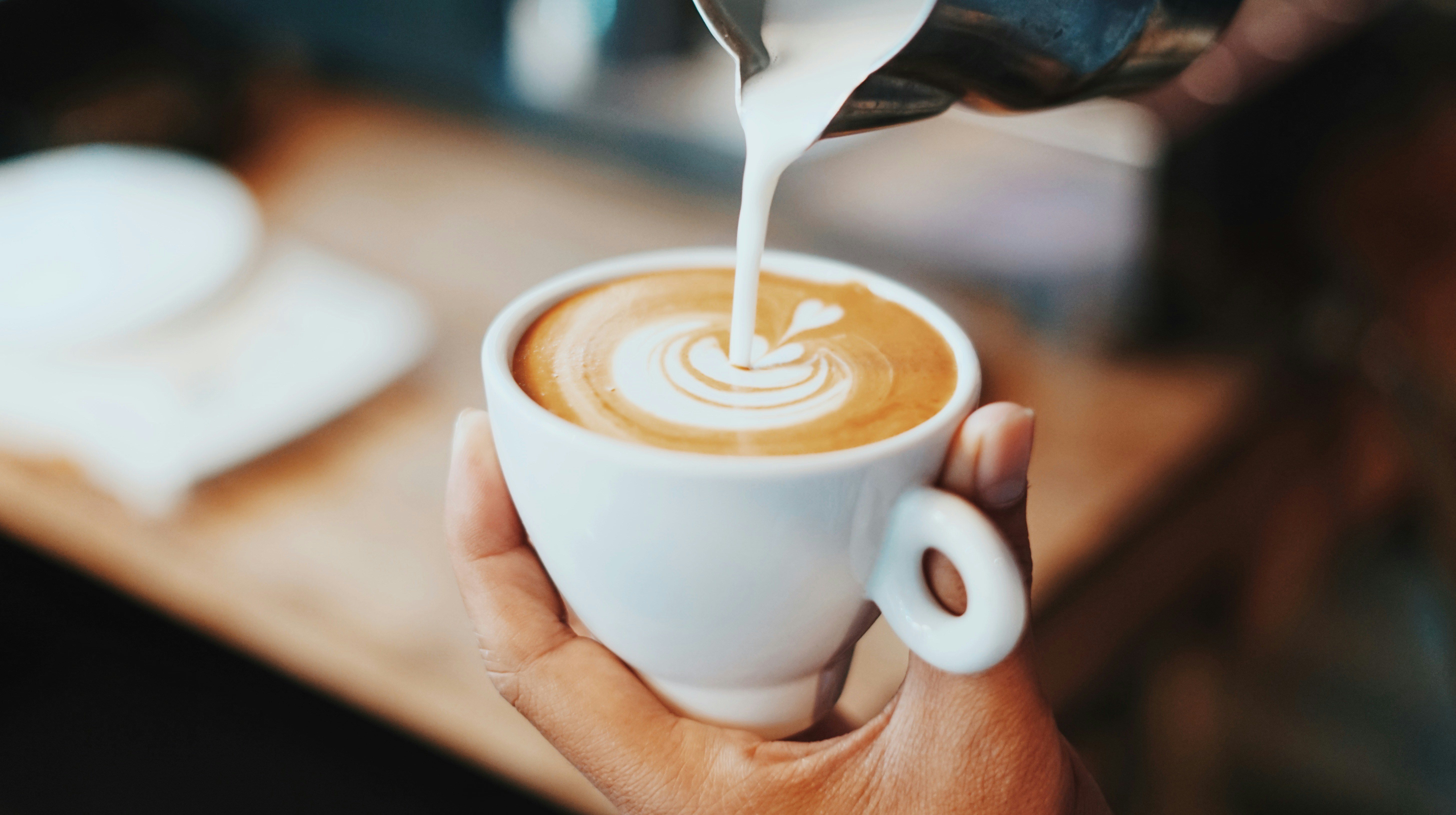 Coffee cup with milk being poured in
