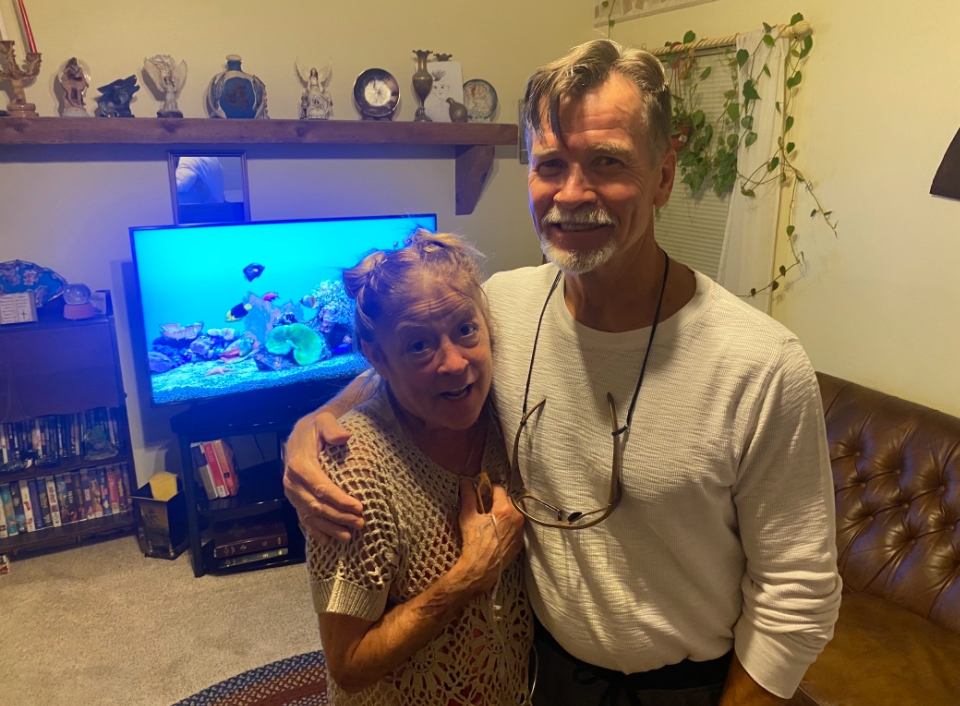 Elderly couple standing smiling in their living room